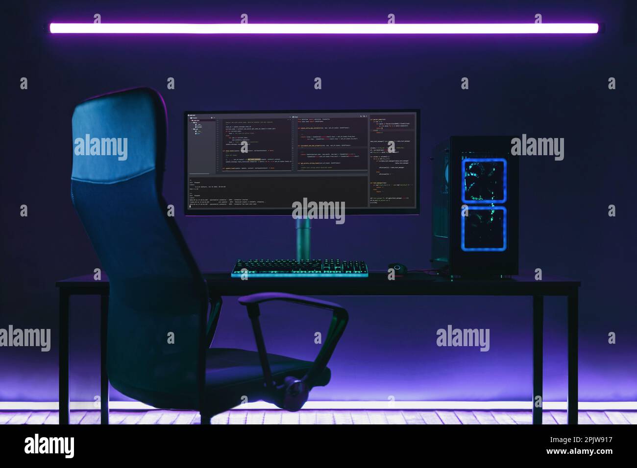 Programmatore per ufficio domestico con configurazione di codifica professionale sul desktop. PC e display moderni e potenti con codice di programmazione in studio di codifica in luci al neon. Foto Stock