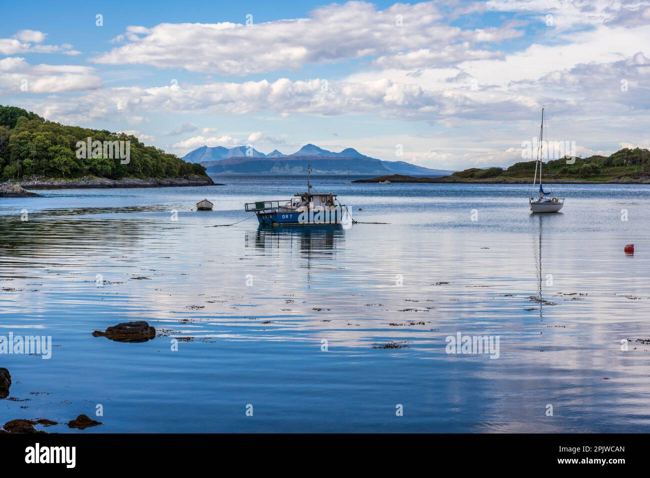 Barche ormeggiate a Samalaman Bay, con l'isola di Eigg in distanza e montagne di Rum oltre, a Glenuig sulla penisola di Ardnamurchan a Lochaber, Scozia Foto Stock
