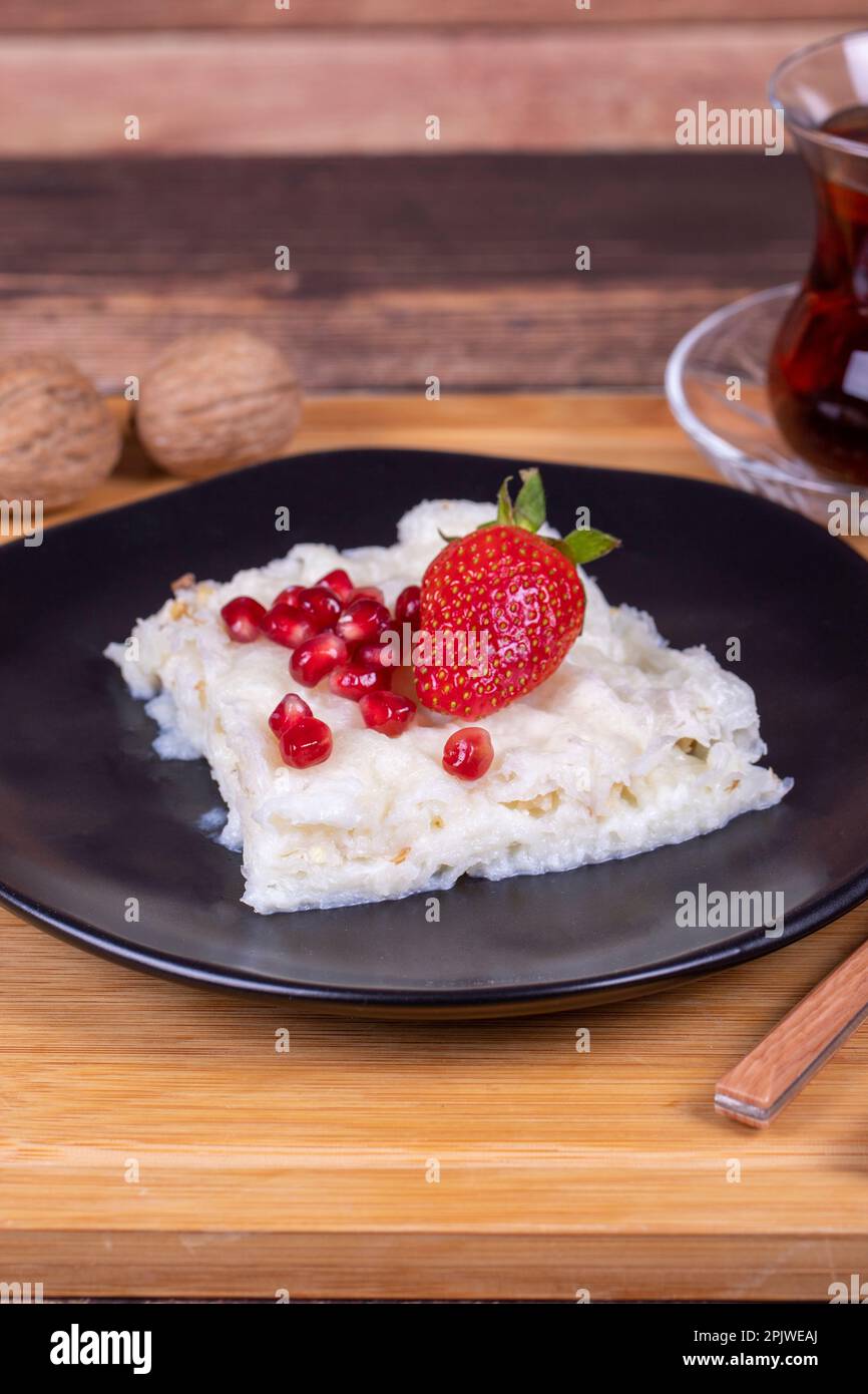 Güllaç dessert con melograno e fragola. Dessert Ramadan. Dessert Gullac con noci su sfondo di legno. Primo piano Foto Stock