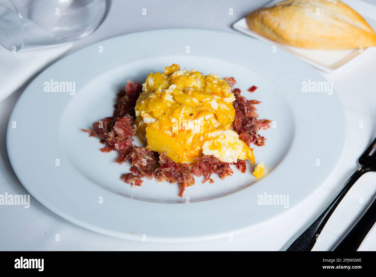 Uova fritte con patatine fritte e prosciutto di serrano. Tradizionale tapa spagnola soprannominata Huevos Rotos. Foto Stock