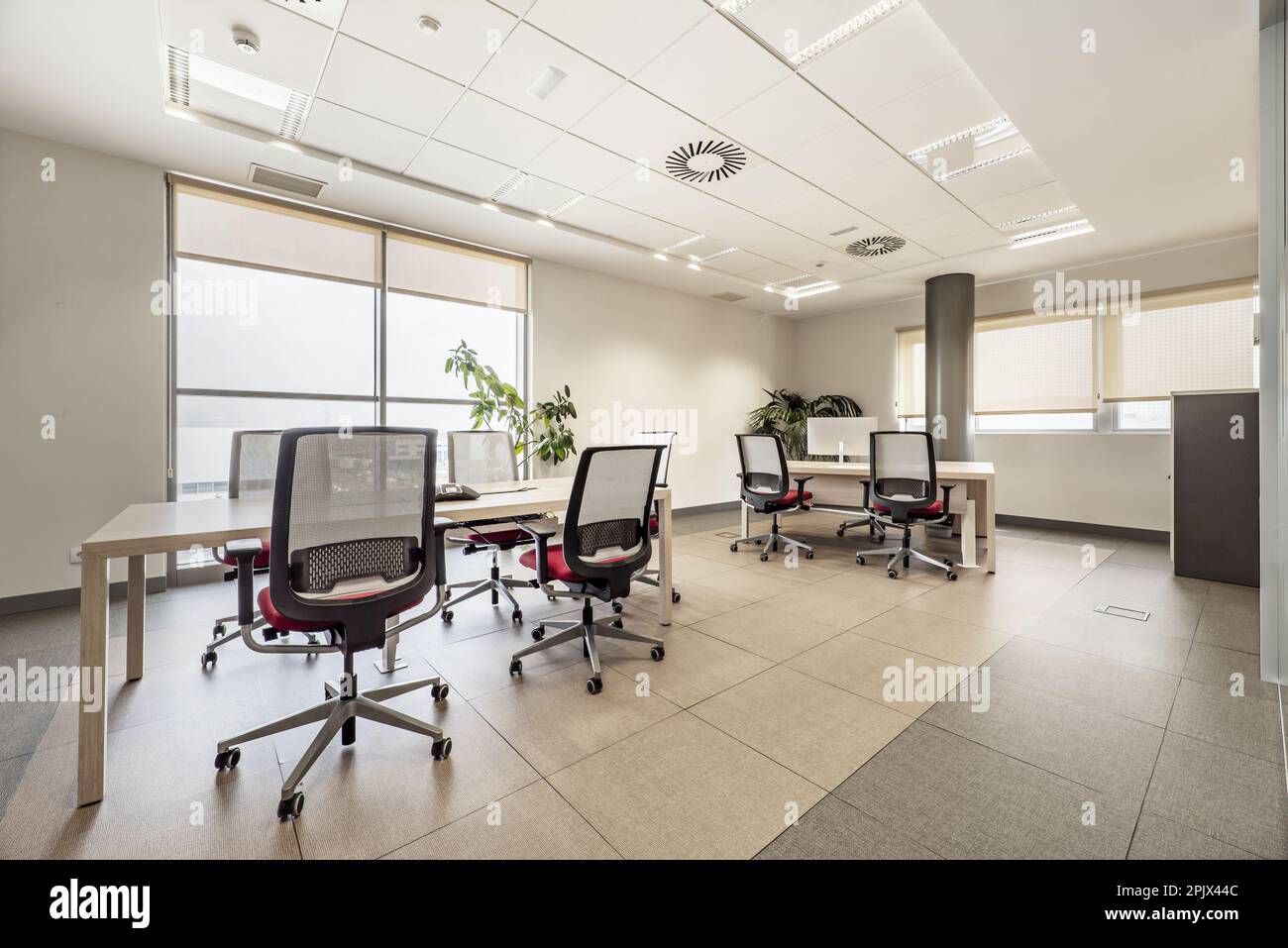 Ufficio professionale con grandi finestre, soffitti tecnici, tavoli da riunione in legno e sedie girevoli identiche Foto Stock