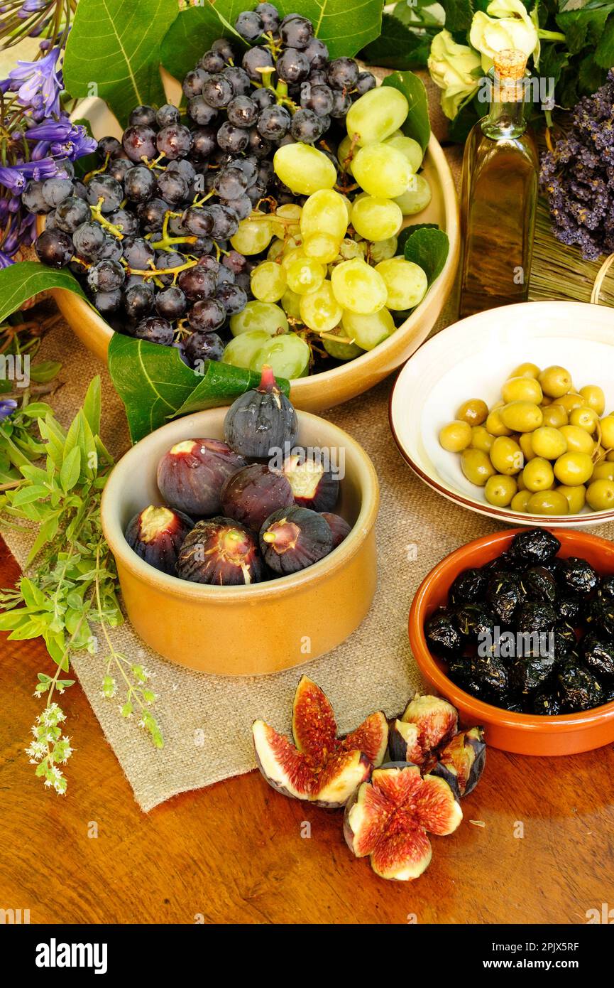 Tavola dei prodotti del giardino provenzale con olive, fichi, uva ed erbe aromatiche, Vaucluse, Francia. Foto Stock
