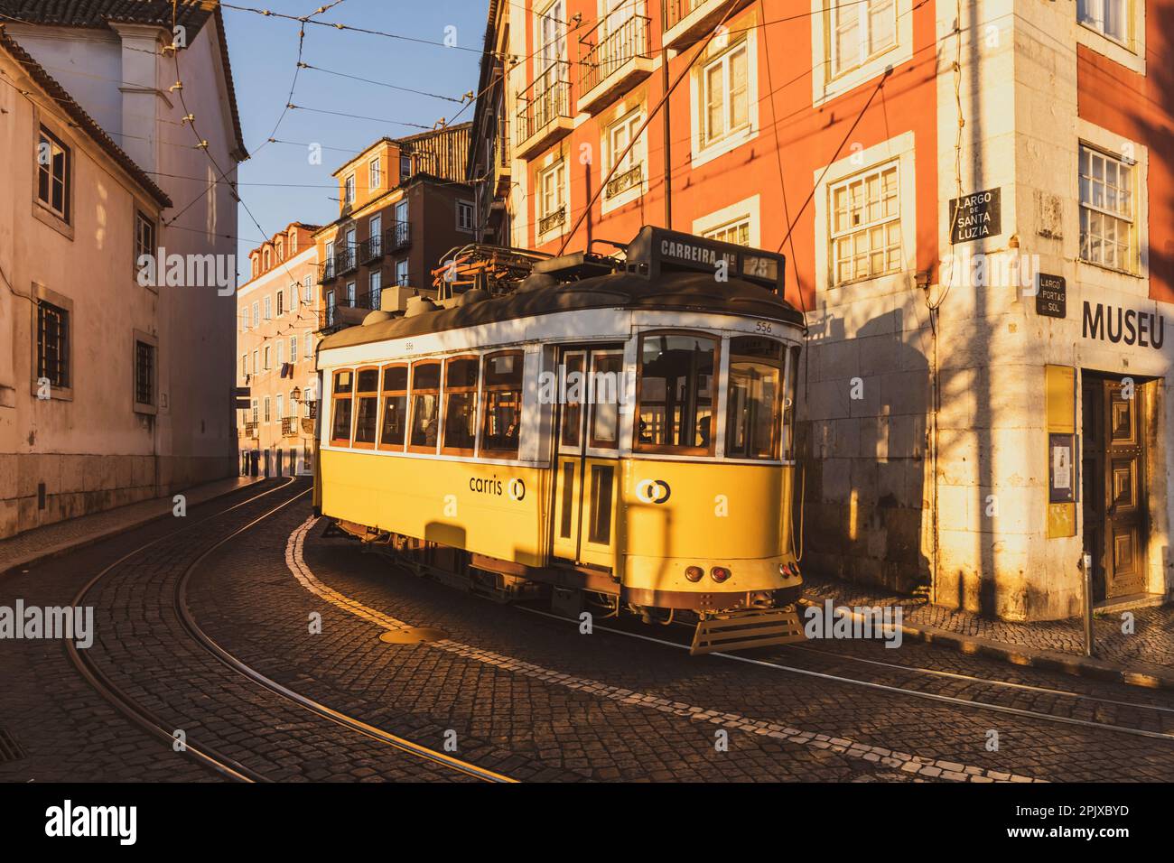 Tram giallo vintage 28 a Largo de Santa Luzia vicino a Miradouro das Portas do Sol, quartiere di Alfama, Lisbona, Portogallo. Foto Stock