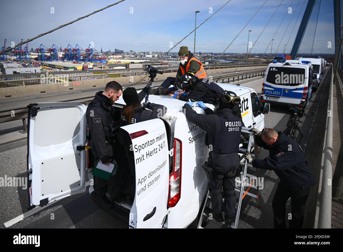 Amburgo, Germania. 04th Apr, 2023. Gli agenti di polizia slegano le mani di un attivista del clima bloccato sul tetto di un furgone. Diversi attivisti del clima hanno bloccato il traffico sul ponte Köhlbrand di Amburgo. Credit: Jonas Walzberg/dpa/Alamy Live News Foto Stock