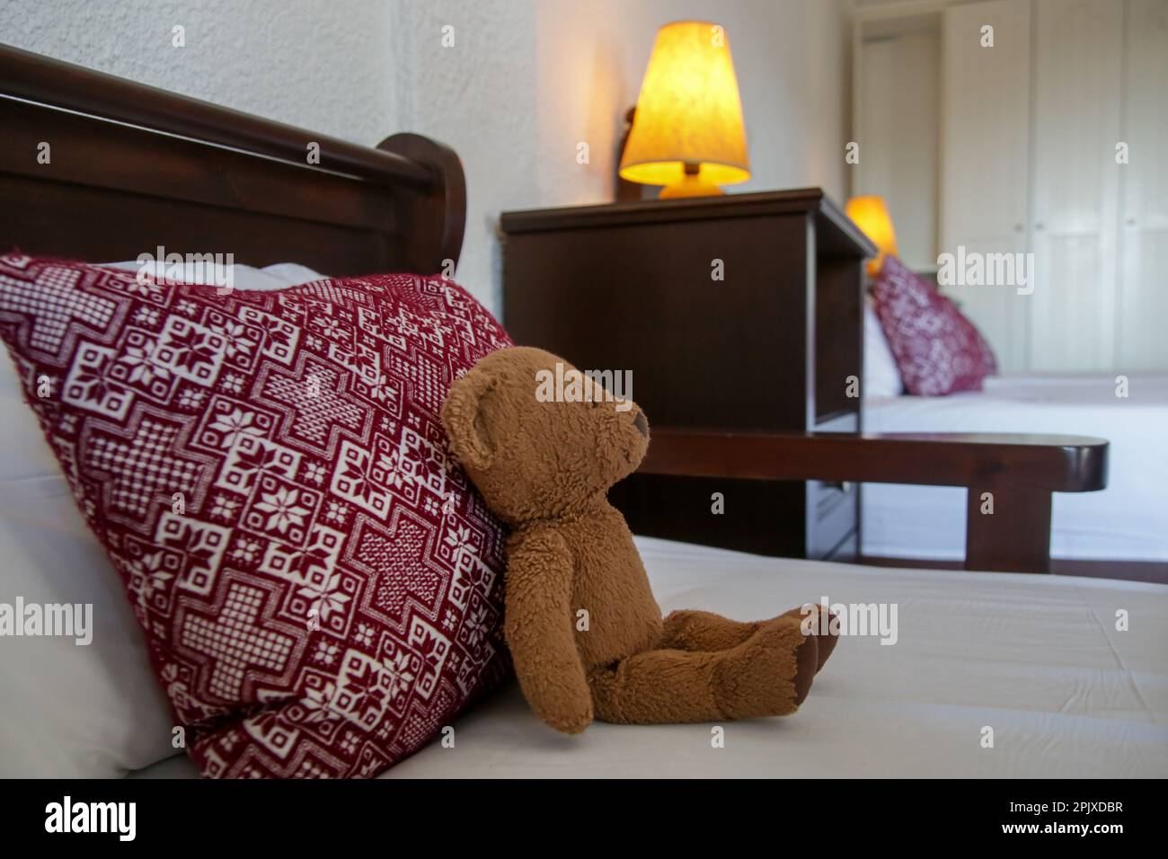 Camera da letto in stile retrò con cuscini dal design rosso e orsacchiotto marrone sul letto Foto Stock