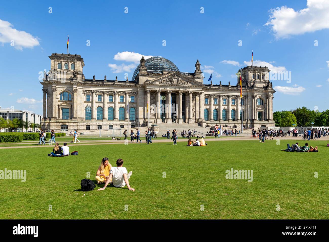 Persone che si rilassano sull'erba di fronte all'edificio del Reichstag, sede del Parlamento tedesco (Deutscher Bundestag). Berlino, Gemany - 28 aprile 2018 Foto Stock
