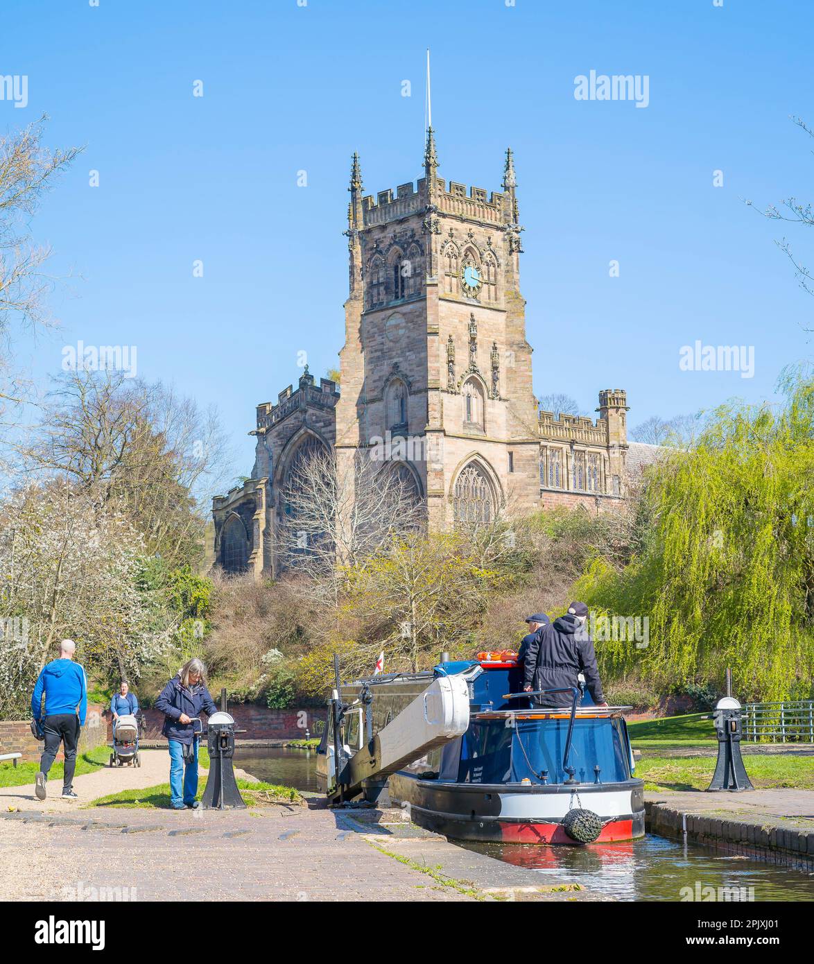 Kidderminster, Regno Unito. 4th aprile 2023. Tempo nel Regno Unito: L'abbondanza di sole primaverile e cielo blu rende per una giornata perfetta sull'acqua. Una famiglia e amici sono tutti a bordo del loro battello canale mentre passano attraverso una serratura con la Chiesa di Santa Maria in Kidderminster sullo sfondo. Credit: Lee Hudson/Alamy Live News Foto Stock