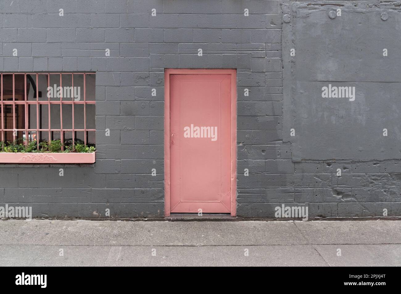 Porta rosa in un vicolo a muro di mattoni grigi con una finestra nel centro di Seattle, Washington Foto Stock