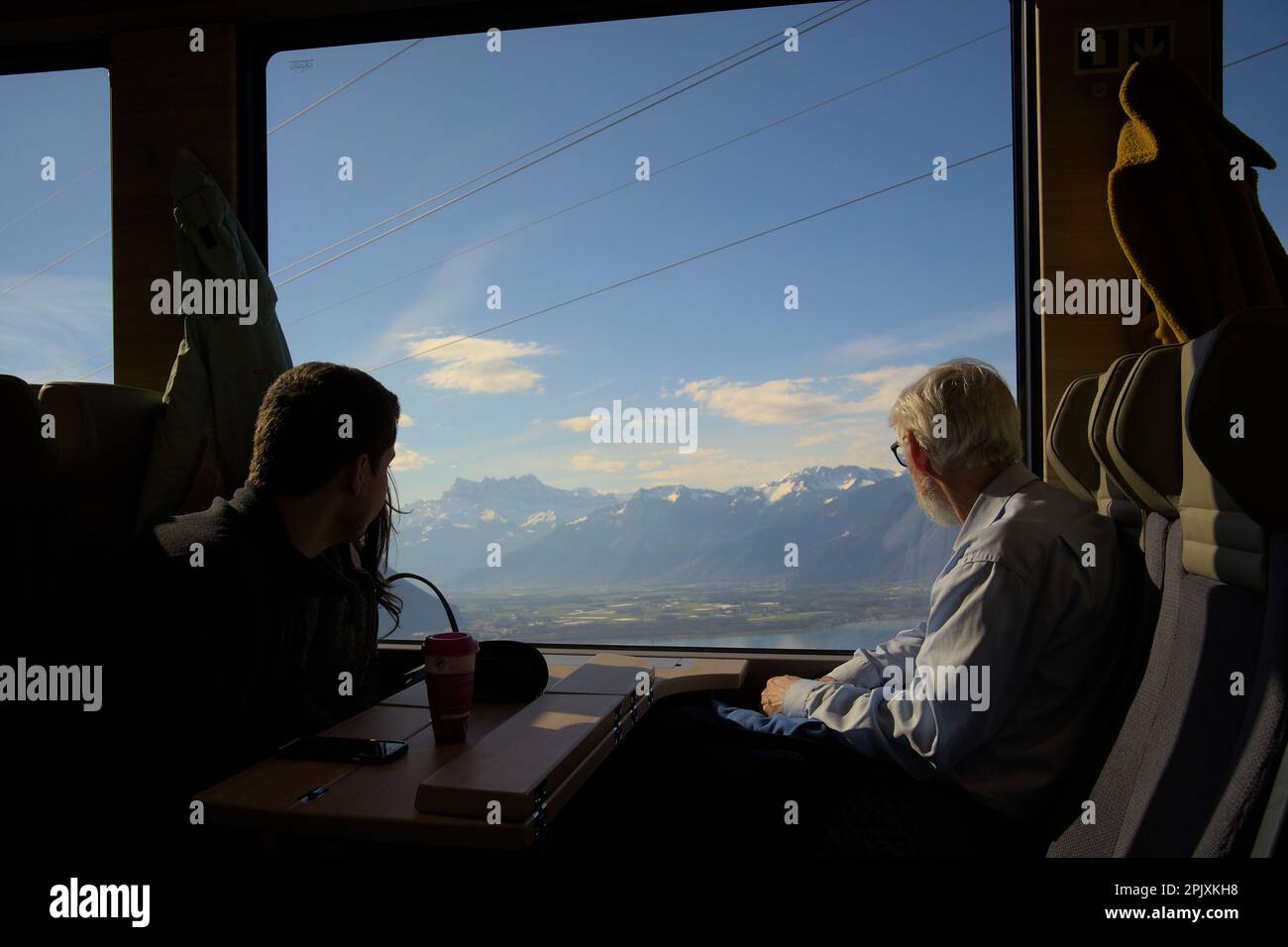 Vecchio e una coppia godendo la vista delle montagne innevate e del lago di Ginevra in un treno da Montreux a Gstaad con Golden Pass Express Foto Stock