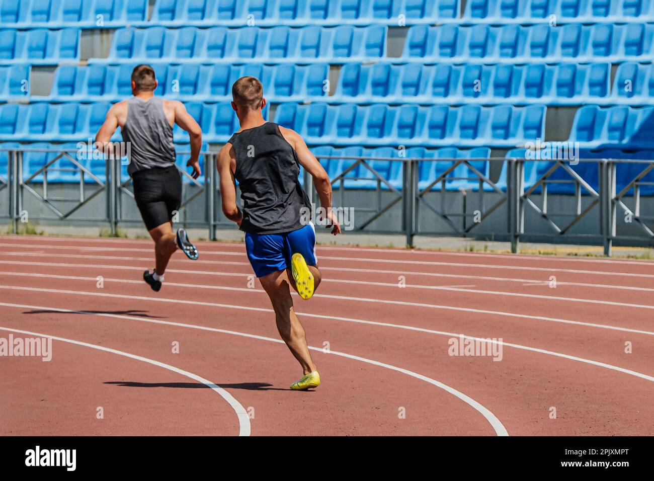 indietro due atleti di decathlon che corrono la pista di corsa di sprint, i campionati di atletica estivi allo stadio Foto Stock