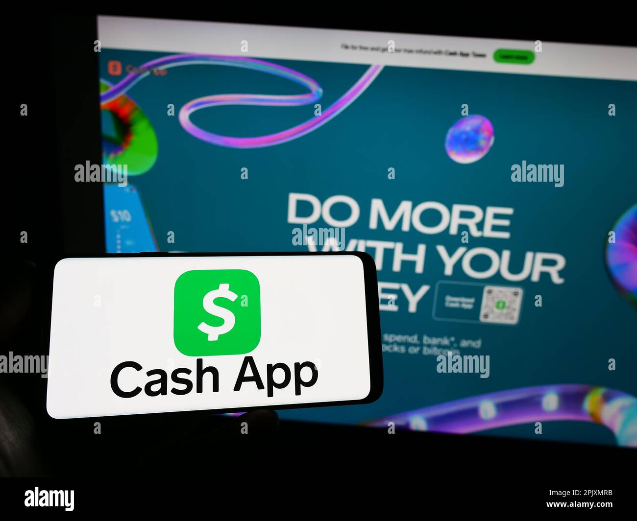 Persona che tiene in mano uno smartphone con il logo della società fintech statunitense Cash App Investing LLC sullo schermo di fronte al sito Web. Messa a fuoco sul display del telefono. Foto Stock