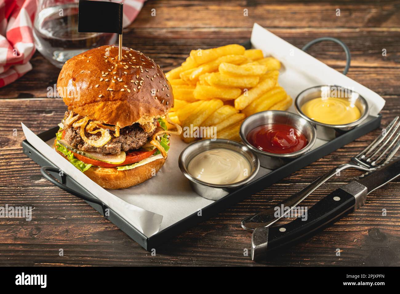Delizioso hamburger alla griglia fatto in casa con manzo, pomodori, formaggio e lattuga su sfondo rustico in legno Foto Stock