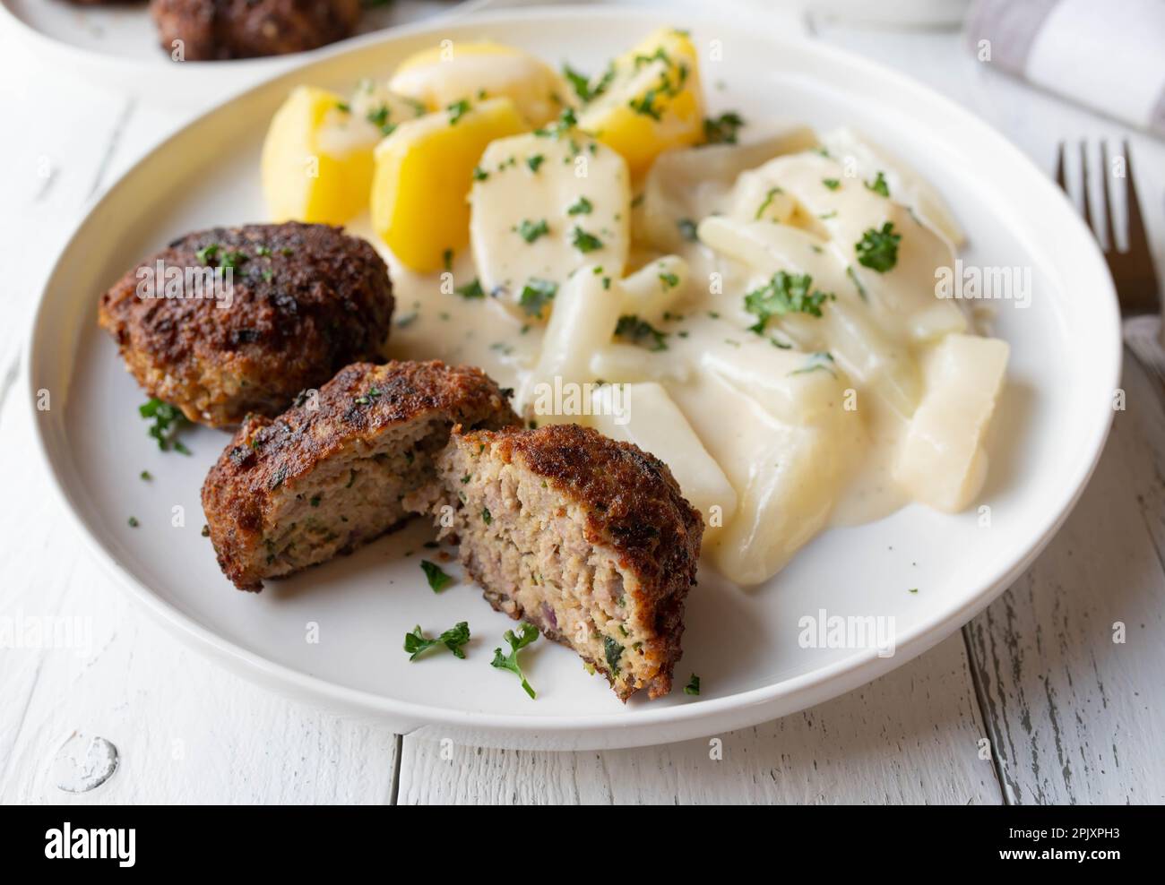 Cucina tradizionale tedesca con polpette di maiale o frikadellen. Servito con kohlrabi cotti e salsa di besciamella e patate bollite su un piatto Foto Stock