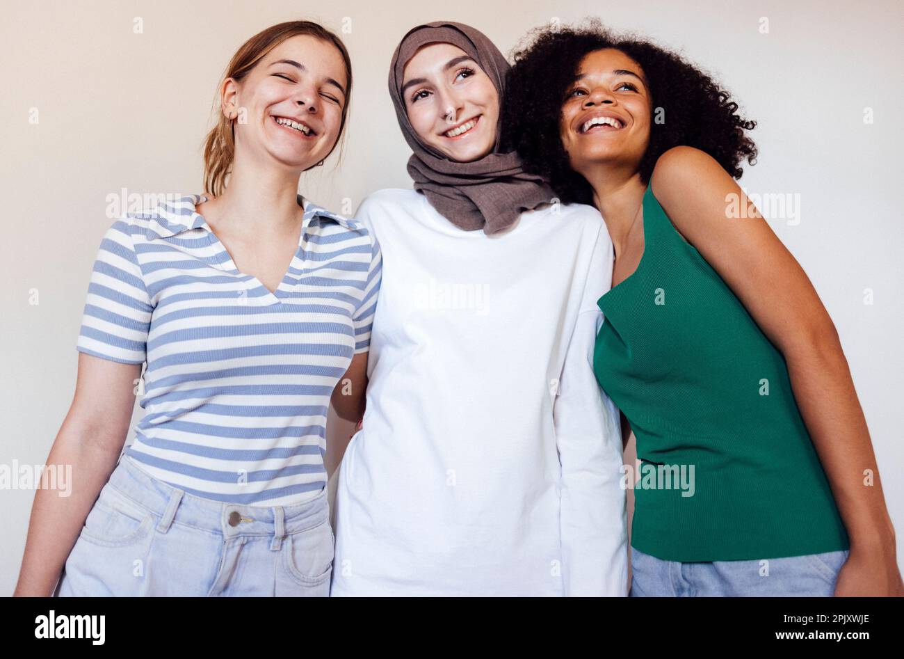 Primo piano ritratti di tre ragazze adolescenti sorridenti. Musulmano in un hijab, afro americano e femmine bianche adolescenti. Ragazze giovani e positive indoor. Venerdì Foto Stock