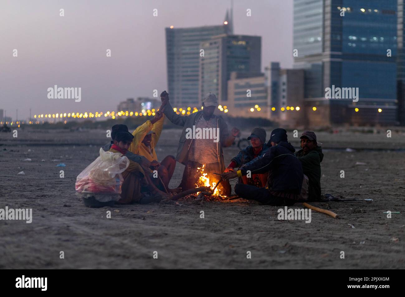 karachi pakistan 2021, Un gruppo di pescatori che fanno falò prima di andare a pescare a vista mare dopo il tramonto in inverni. Foto Stock