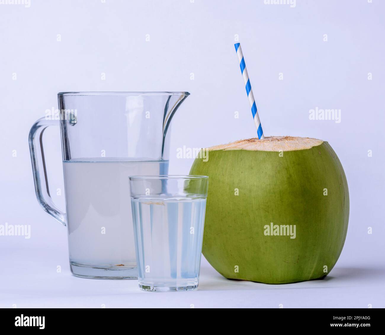 Acqua di cocco. Tazza, vaso e cocco verde su sfondo bianco. Foto Stock