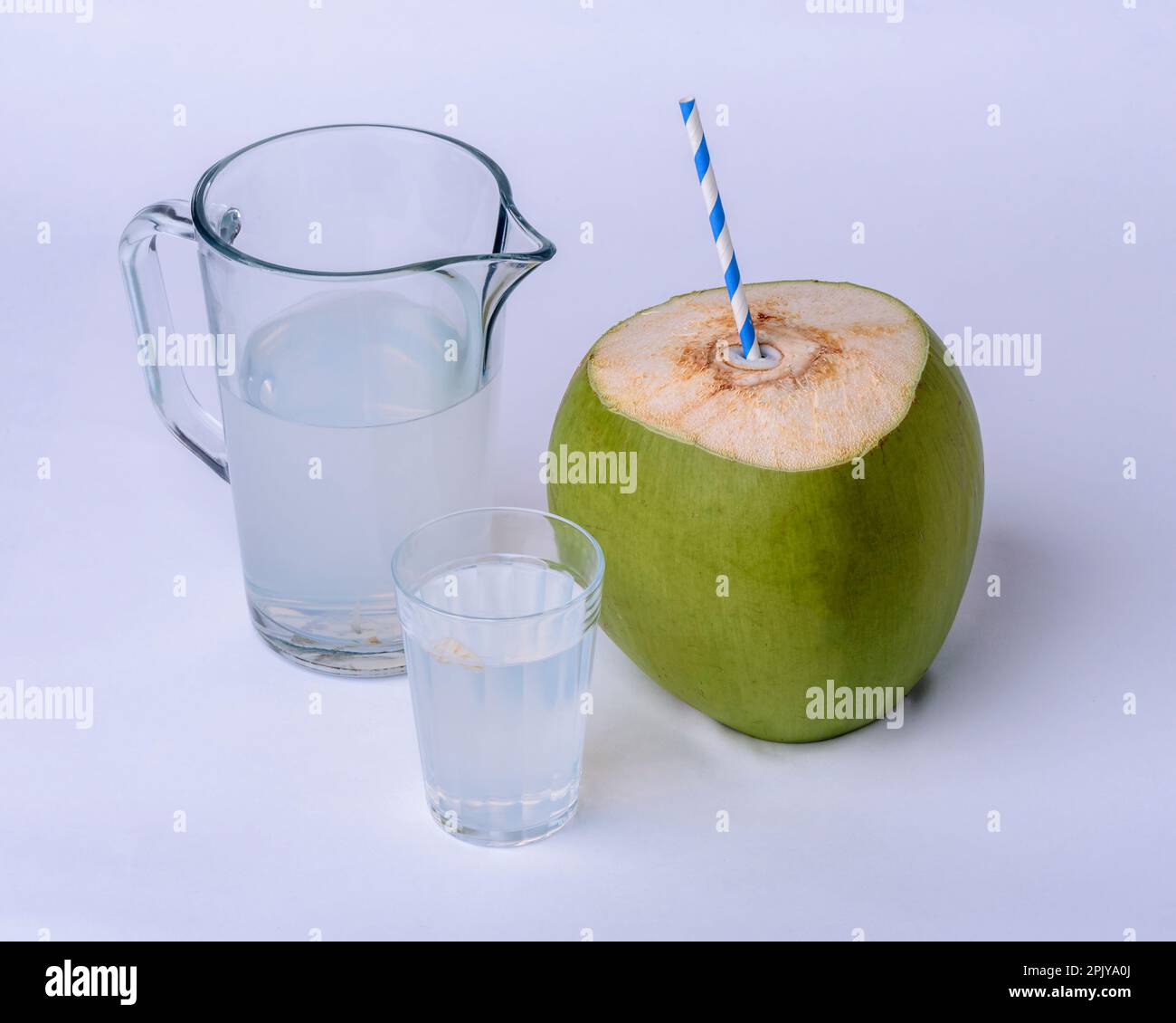 Acqua di cocco. Tazza, vaso e cocco verde su sfondo bianco. Foto Stock