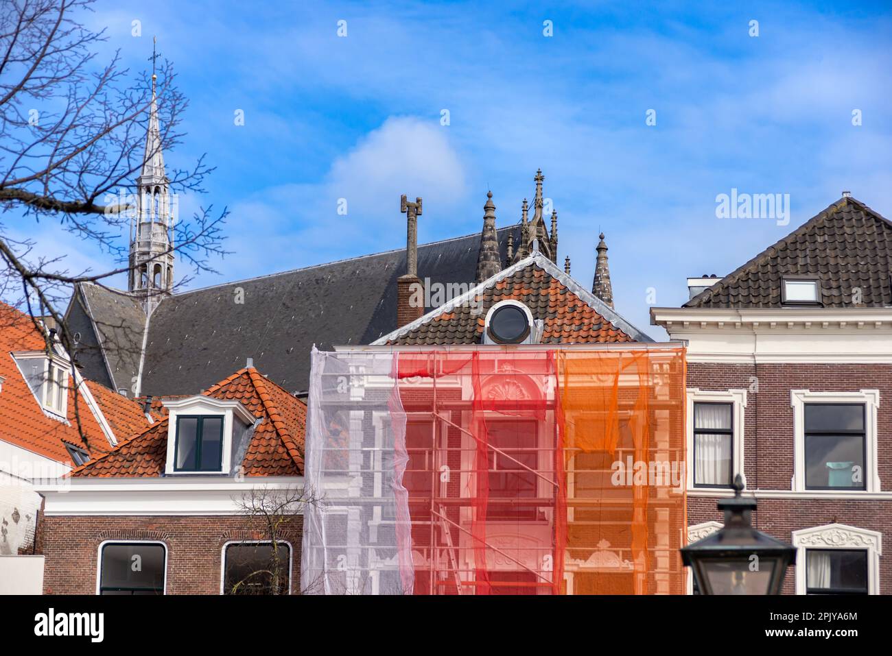 Ponteggi arancioni con rete protettiva contro edifici storici per evitare che la vernice e il materiale da costruzione cadano sulla strada e sulle persone, durante Foto Stock