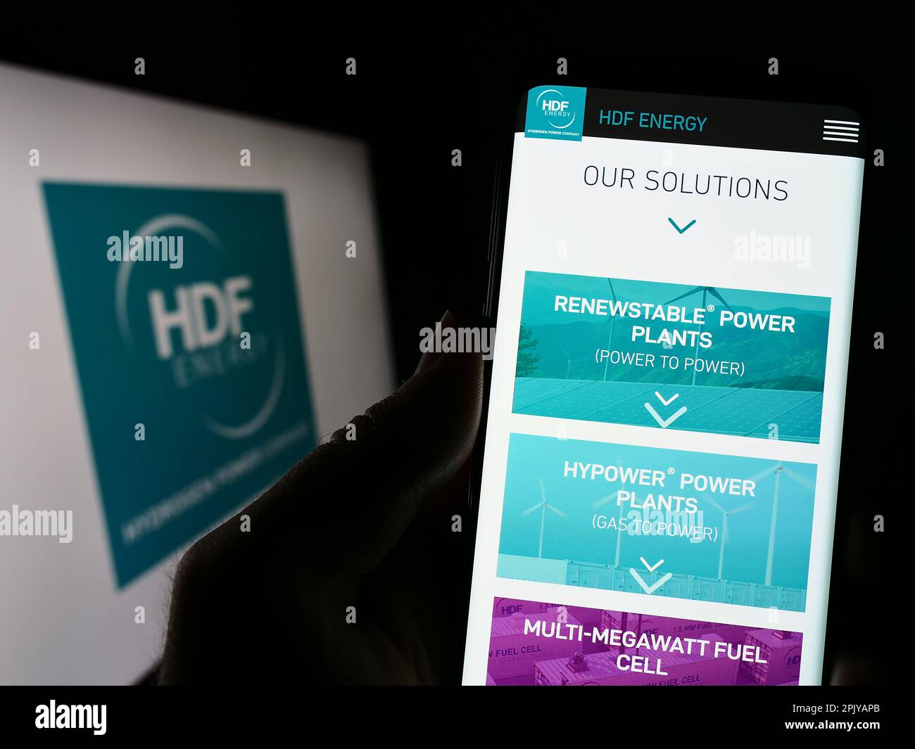 Persona in possesso di smartphone con sito web della società francese di idrogeno HDF energia sullo schermo di fronte al logo. Messa a fuoco al centro del display del telefono. Foto Stock
