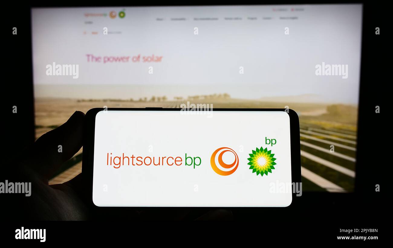 Persona che tiene in mano uno smartphone con il logo della società britannica di energia rinnovabile Lightsource BP sullo schermo di fronte al sito Web. Messa a fuoco sul display del telefono. Foto Stock