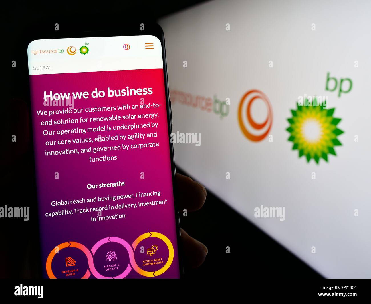 Persona che tiene il cellulare con pagina web della compagnia britannica di energia rinnovabile Lightsource BP sullo schermo con il logo. Messa a fuoco al centro del display del telefono. Foto Stock