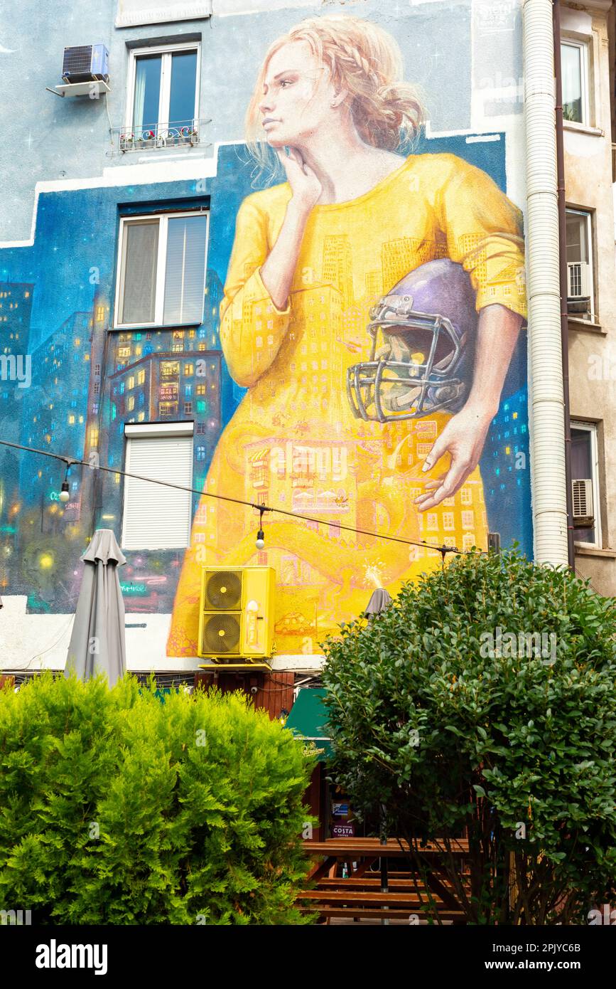 Murale raffigurante una giovane donna in possesso di un casco da calcio americano a Sofia, Bulgaria, Europa orientale, Balcani, UE Foto Stock