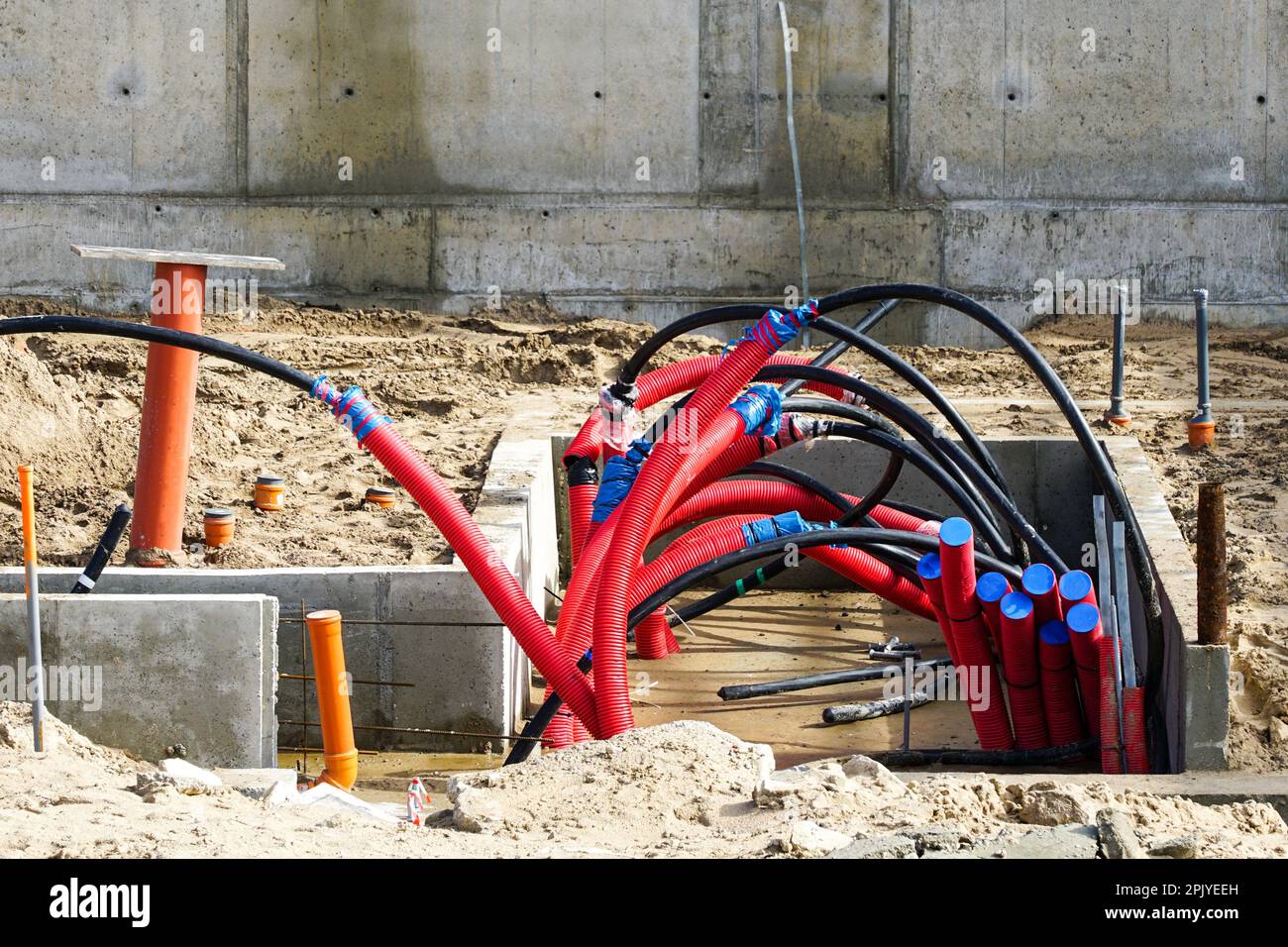 Molti grandi cavi elettrici neri sono assemblati in tubi di protezione  corrugati rossi nel cantiere di un nuovo impianto industriale Foto stock -  Alamy
