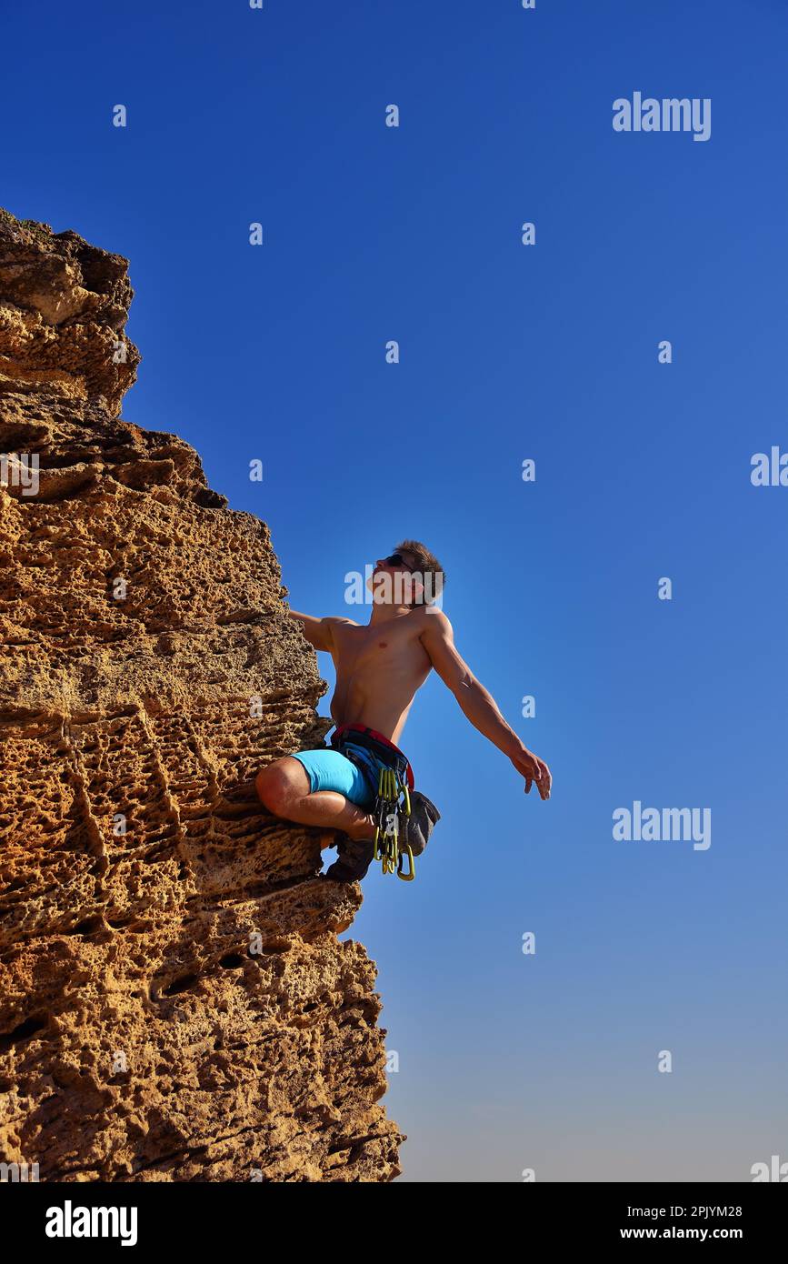 maschio scalatore di roccia sale su una parete rocciosa Foto Stock