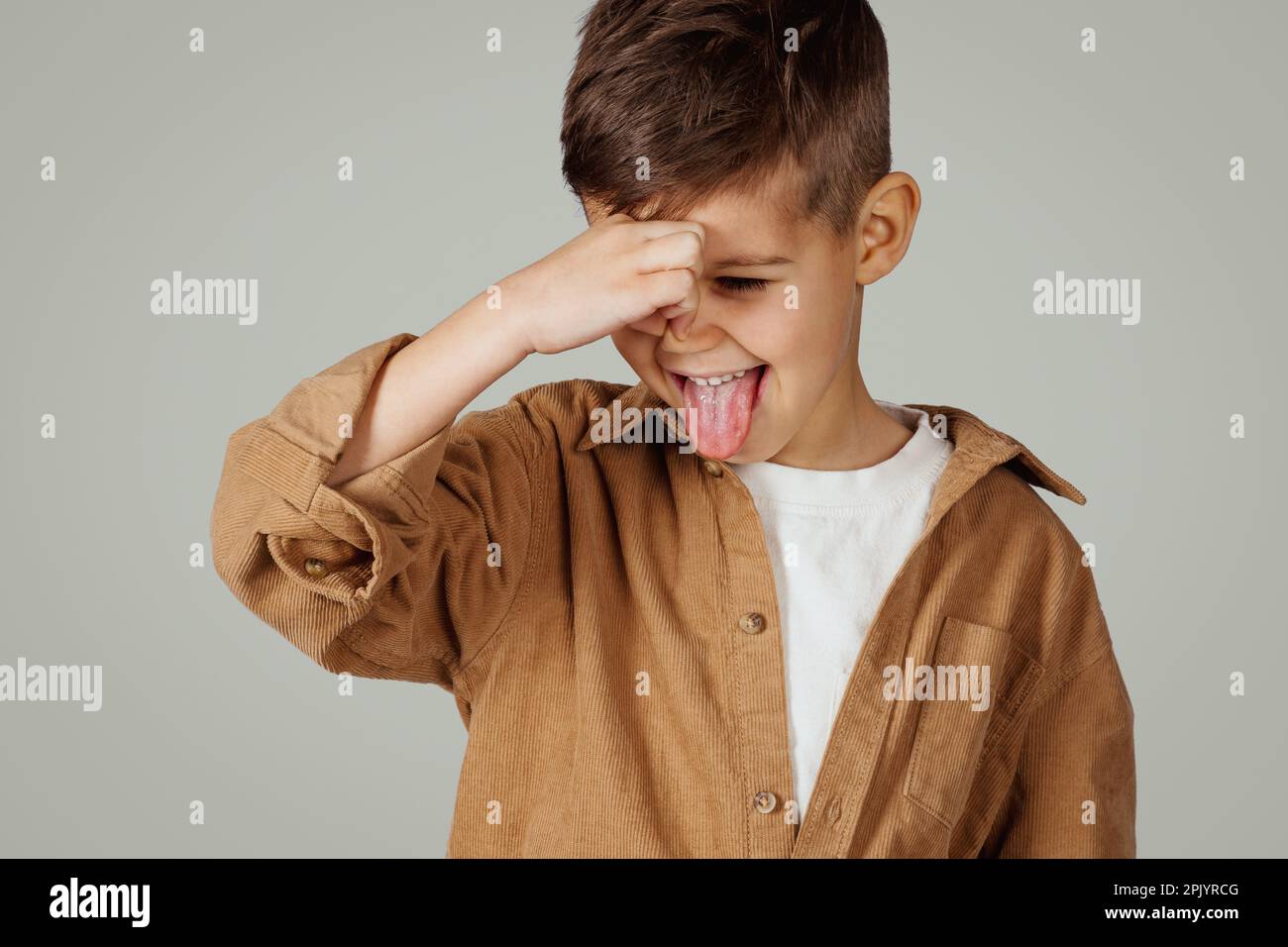 Capretto caucasico disgruntled di 6 anni in casual coprendo il naso con la mano Foto Stock