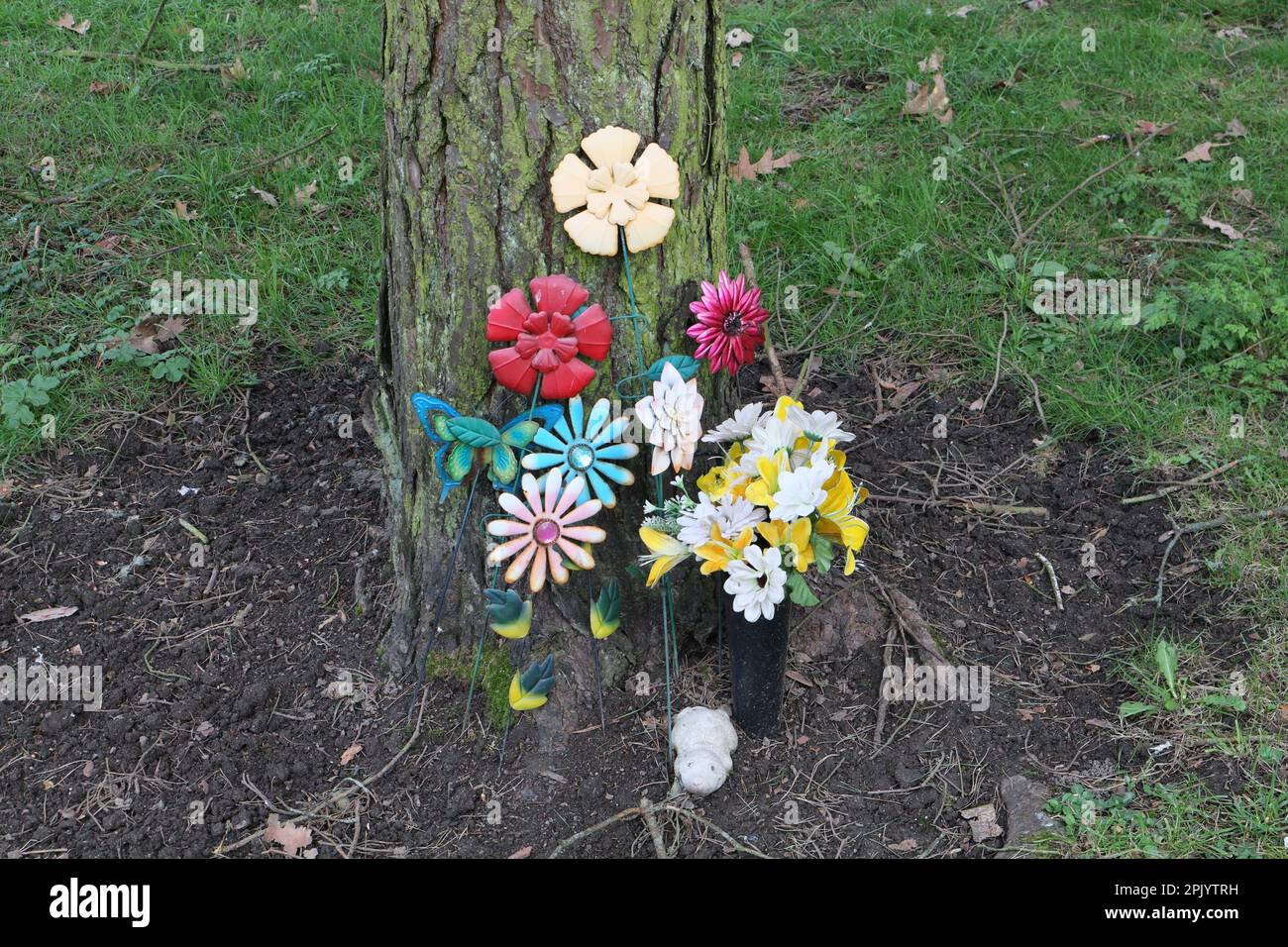 Giardino del ricordo, fiori di plastica colorati da un albero Foto Stock