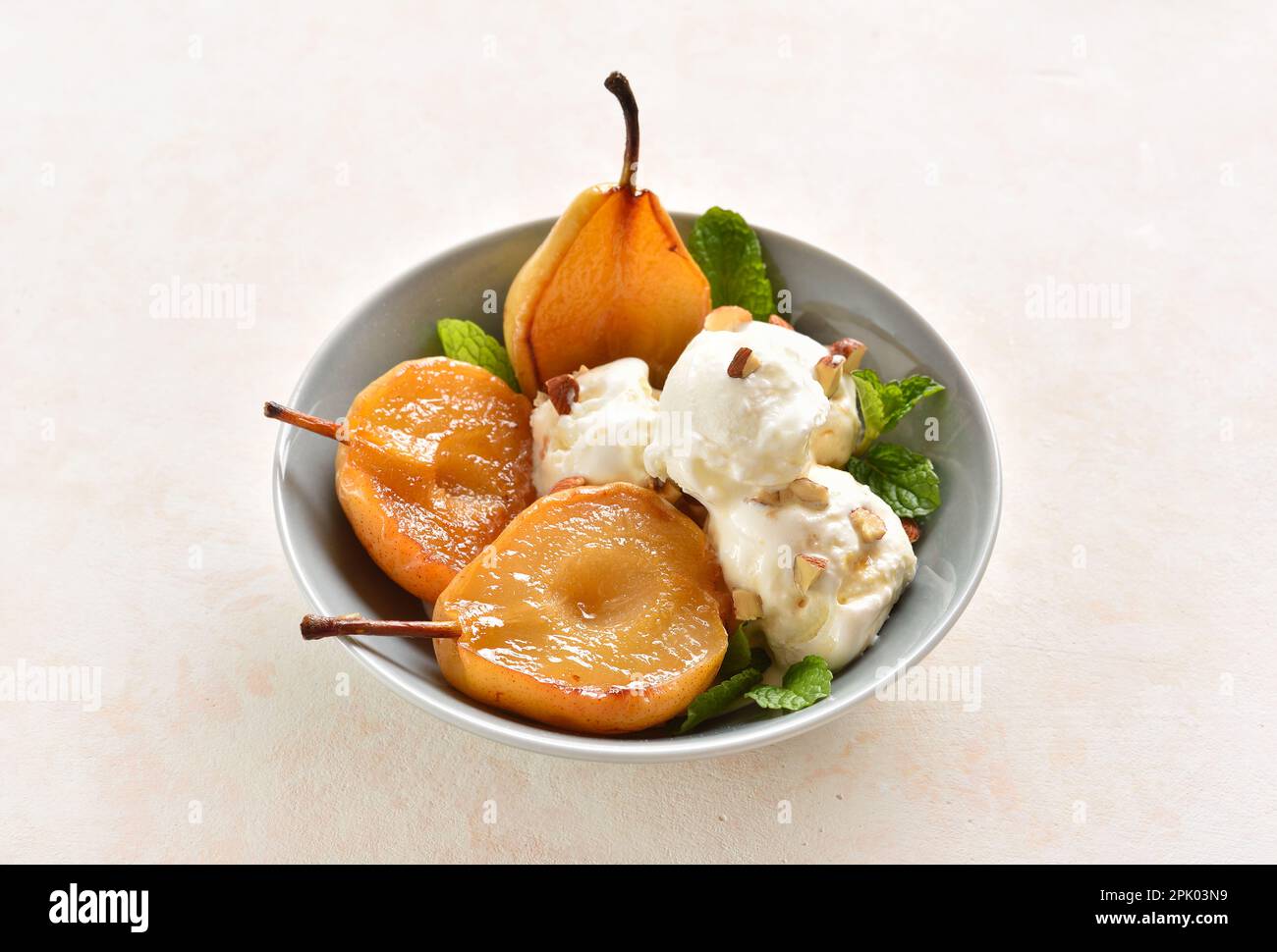 Pere alla vaniglia in camicia con gelato in ciotola su fondo di pietra chiara. Vista ravvicinata Foto Stock
