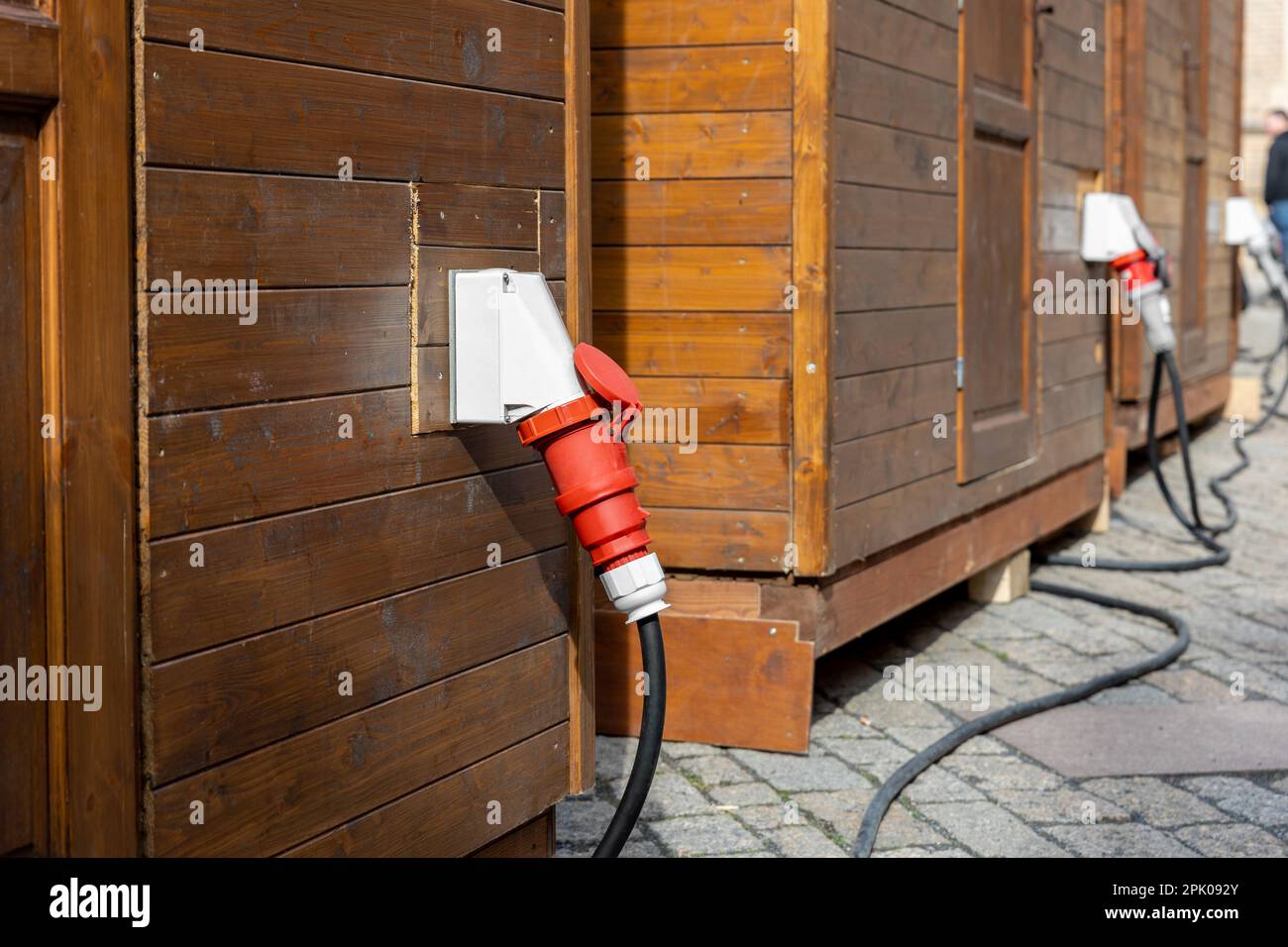 Fila di piccole cabine in legno strada cittadina con prese industriali ad alta tensione a muro cavo elettrico. Energia temporanea 380V waterptoof alimentazione Foto Stock