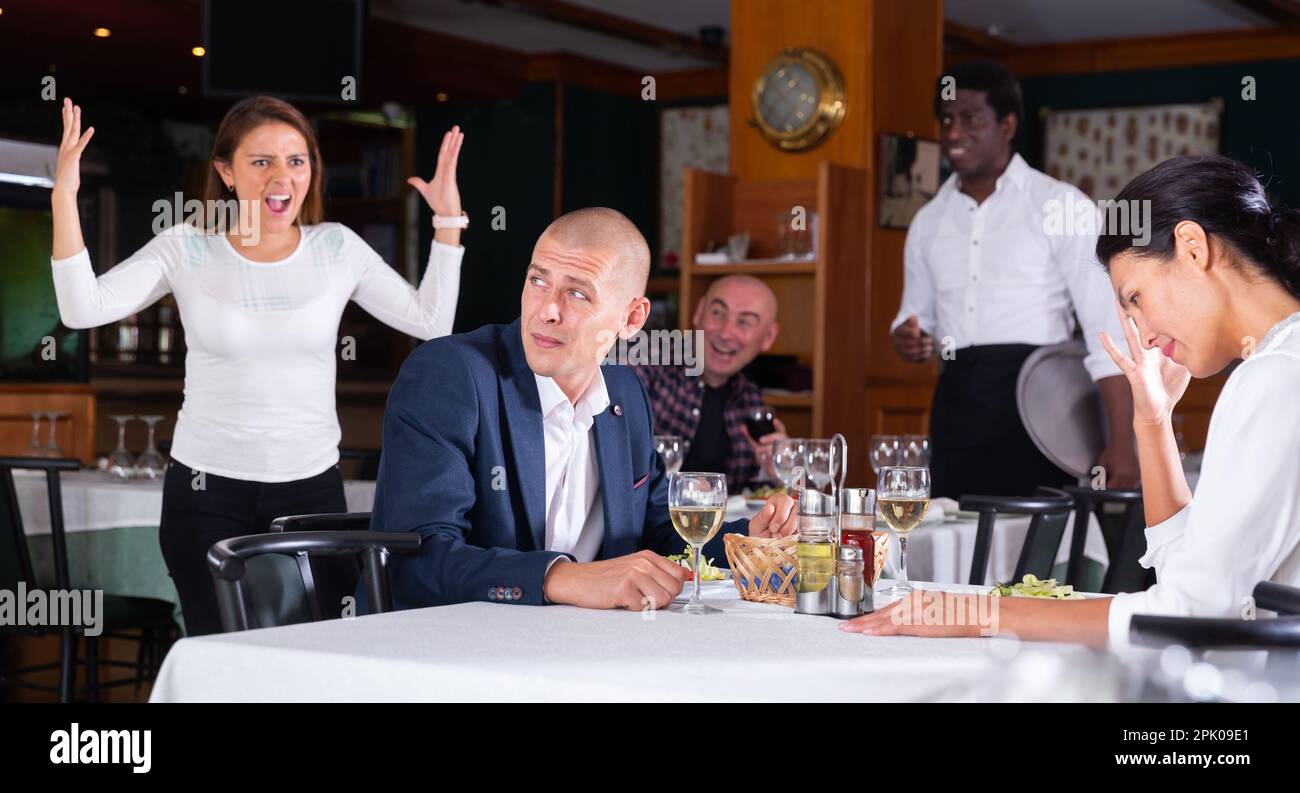 Donna che cattura marito con padrona nel ristorante Foto Stock