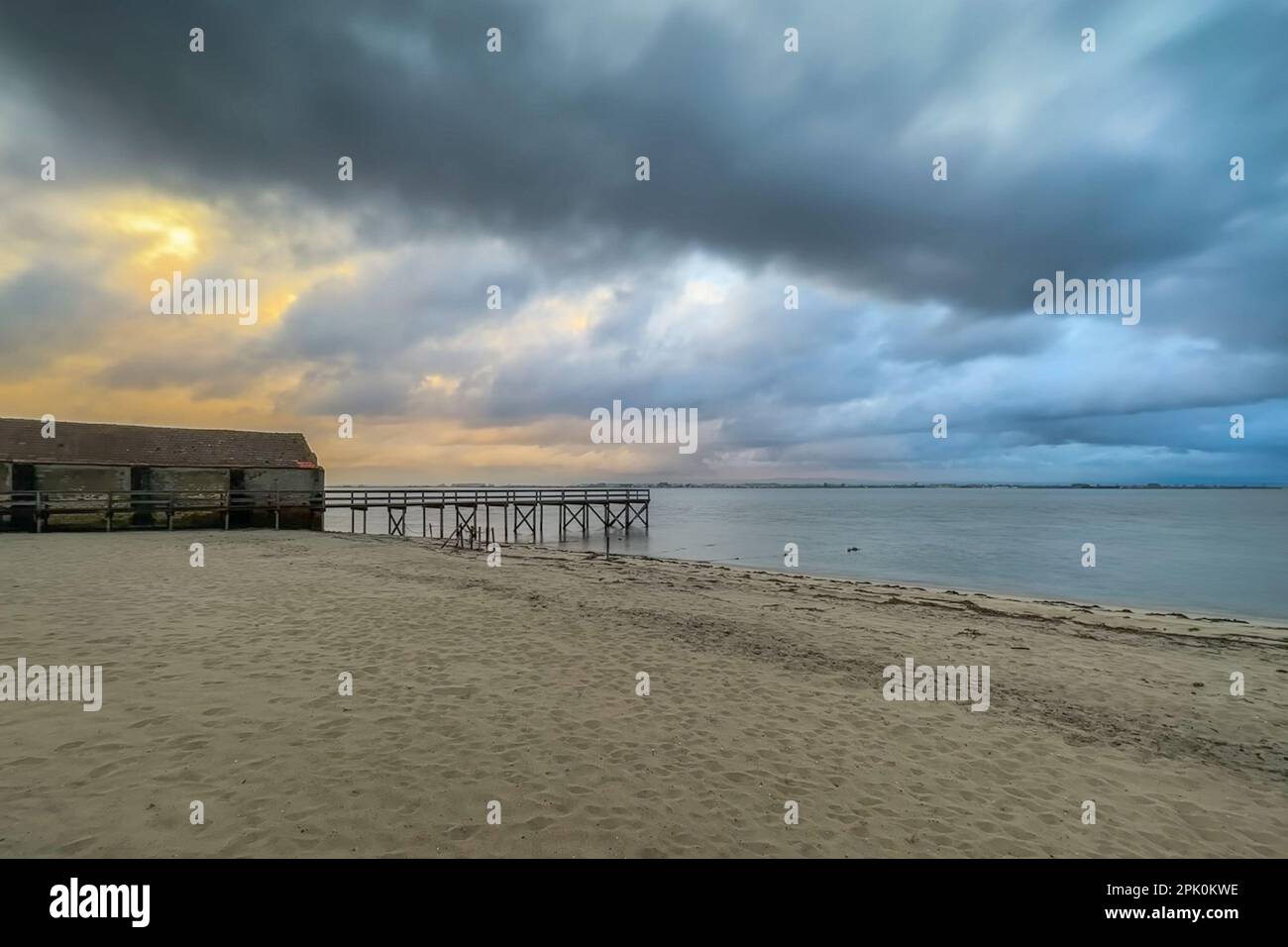 Vuoto molo di legno per il Ria de Aveiro in Portogallo, con cielo drammatico e acqua calma. Torreira, Murtosa - Portogallo. Foto Stock