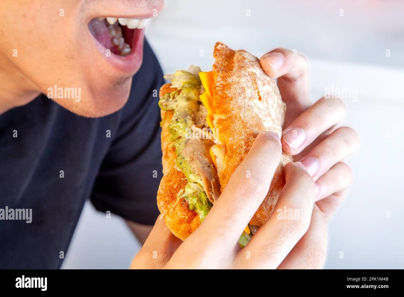 Giovane maschio felice circa per prendere il primo morso di un panino sano di ciabatta. Foto Stock