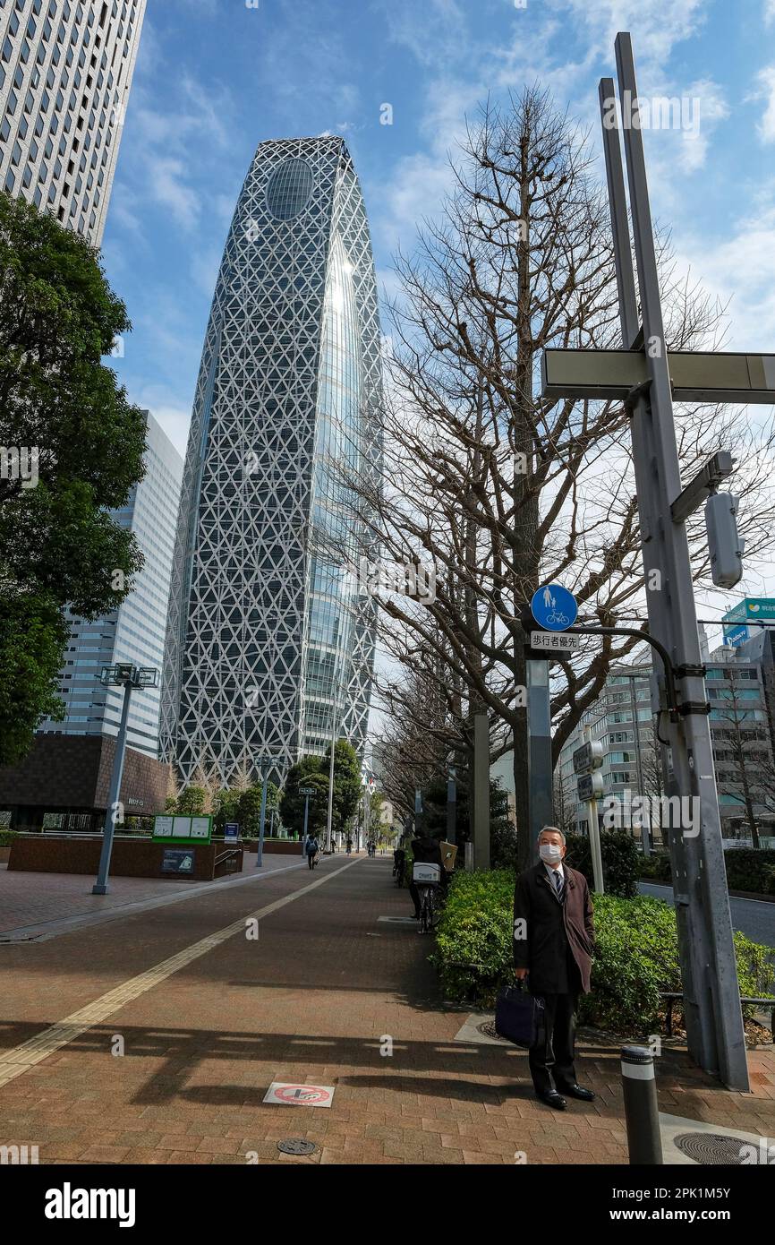 Tokyo, Giappone - 6 marzo 2023: Un uomo d'affari nel quartiere centrale degli affari di Shinjuku con la Mode Gakuen Cocoon Tower sullo sfondo a Tokyo, Foto Stock