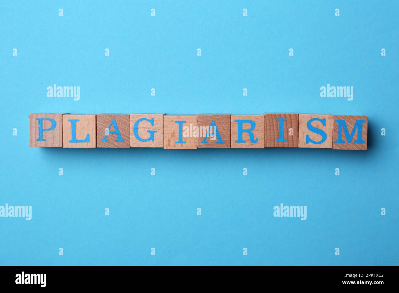 Plagio di parole fatto di cubi di legno con lettere su sfondo azzurro, vista dall'alto Foto Stock