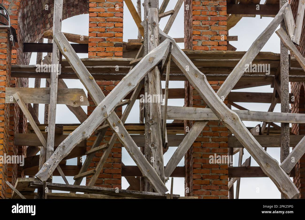 costruzione di un campanile e di una chiesa. Muro di mattoni. Ponteggi in legno Foto Stock