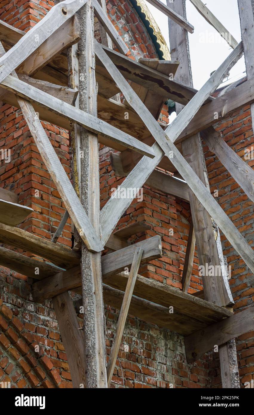 costruzione di un campanile e di una chiesa. Muro di mattoni. Ponteggi in legno Foto Stock