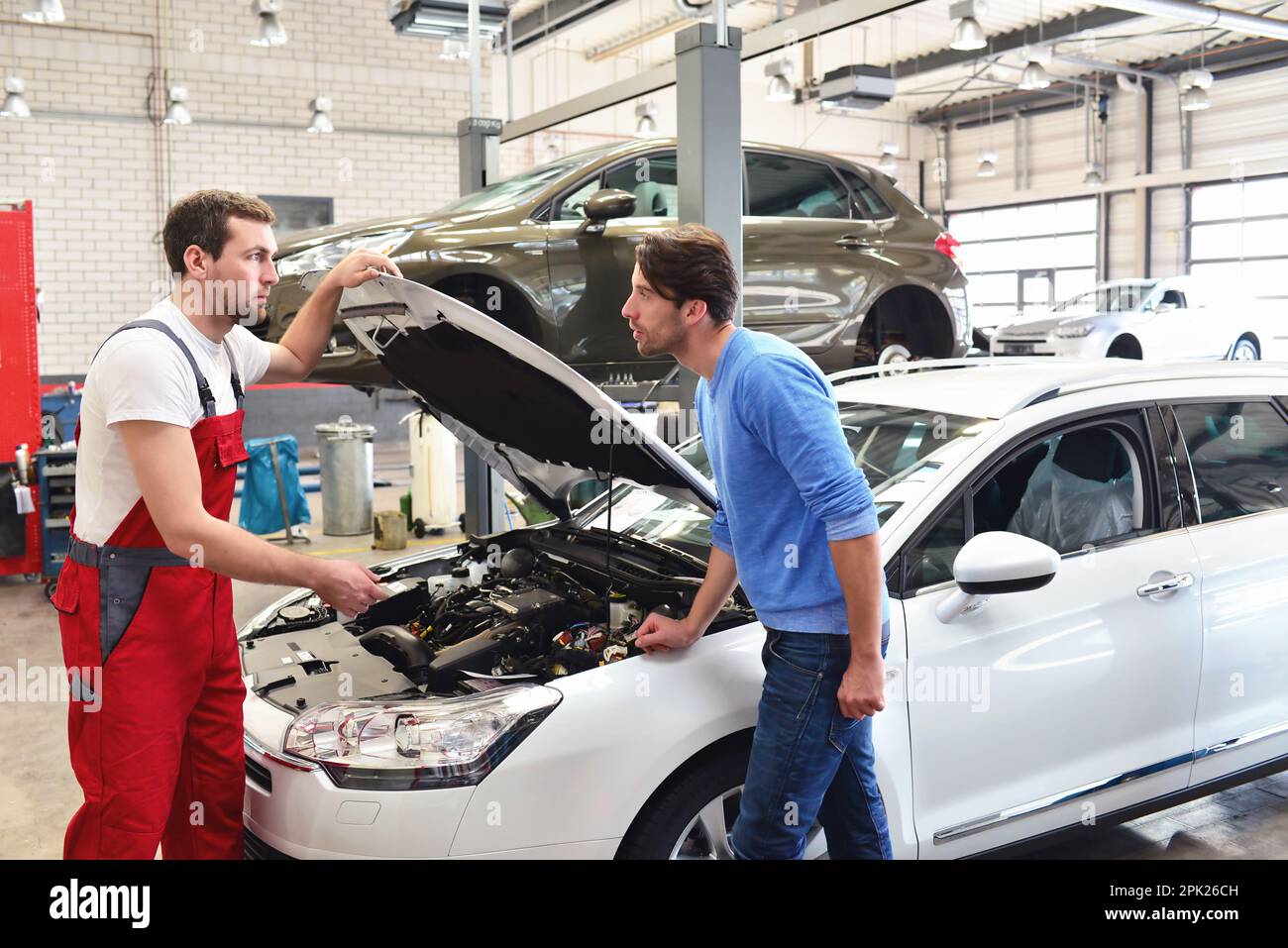 Servizio di assistenza post-vendita in riparazione auto shop - meccanico e l'uomo parla di riparazione di un veicolo Foto Stock