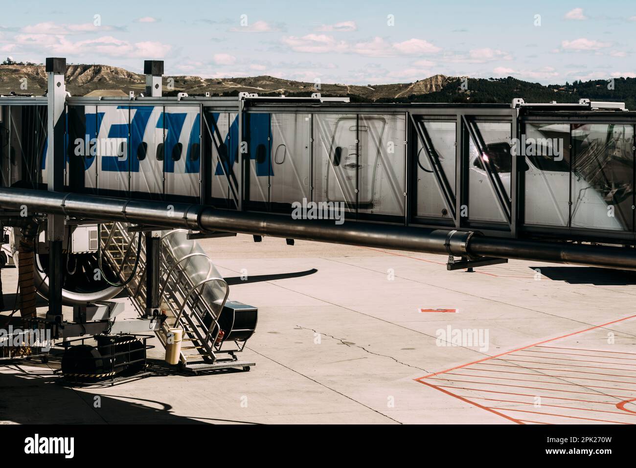 Parcheggio aereo vuoto ponte aereo passeggeri al grembiule dell'aeroporto sullo sfondo di un bel cielo - riflettendo con l'aereo Foto Stock
