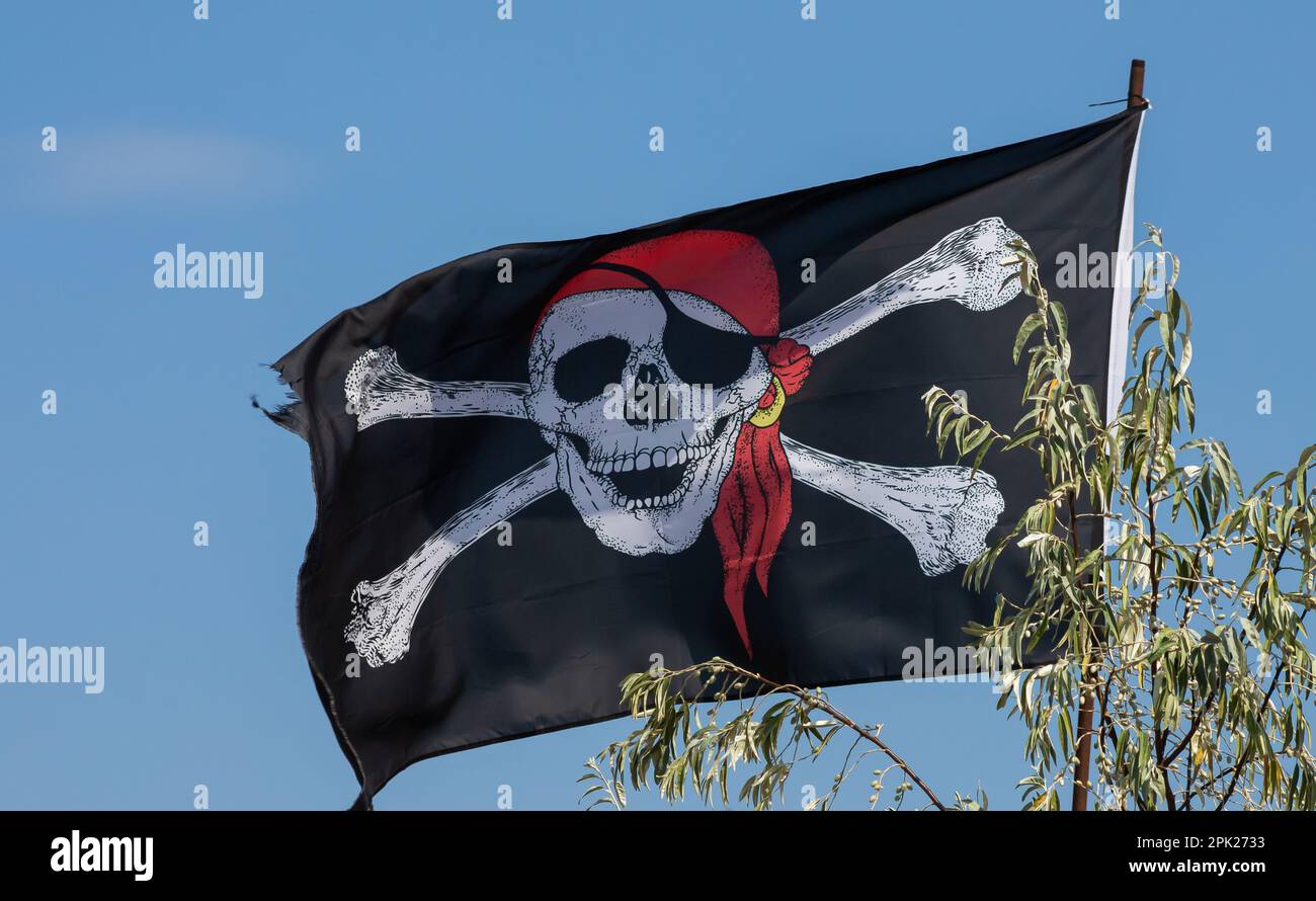 Un cranio e ossa incrociate pirata bandiera che ondola nel vento. Foto Stock