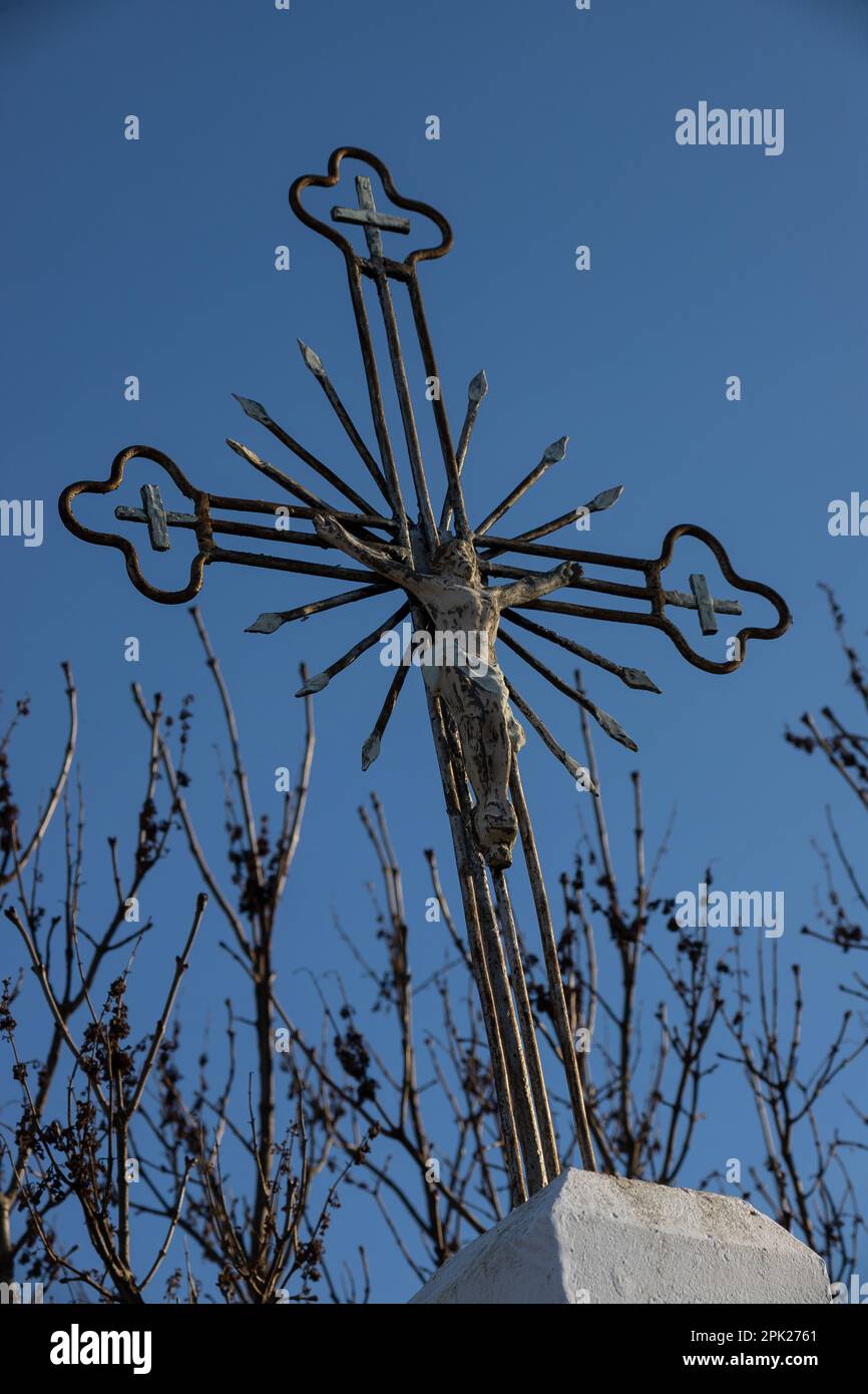 Vecchia croce di metallo con un crocifisso su uno sfondo cielo senza nuvole. Immagine verticale. Foto Stock