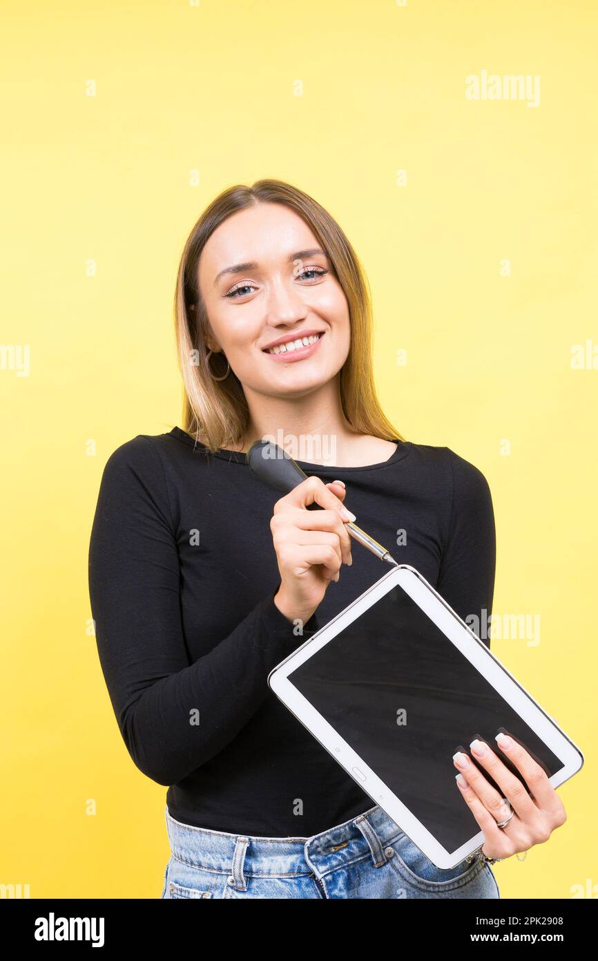 Centro servizi. Riparazione del notebook. Il cacciavite femmina svita i bulloni del computer portatile su sfondo giallo Foto Stock