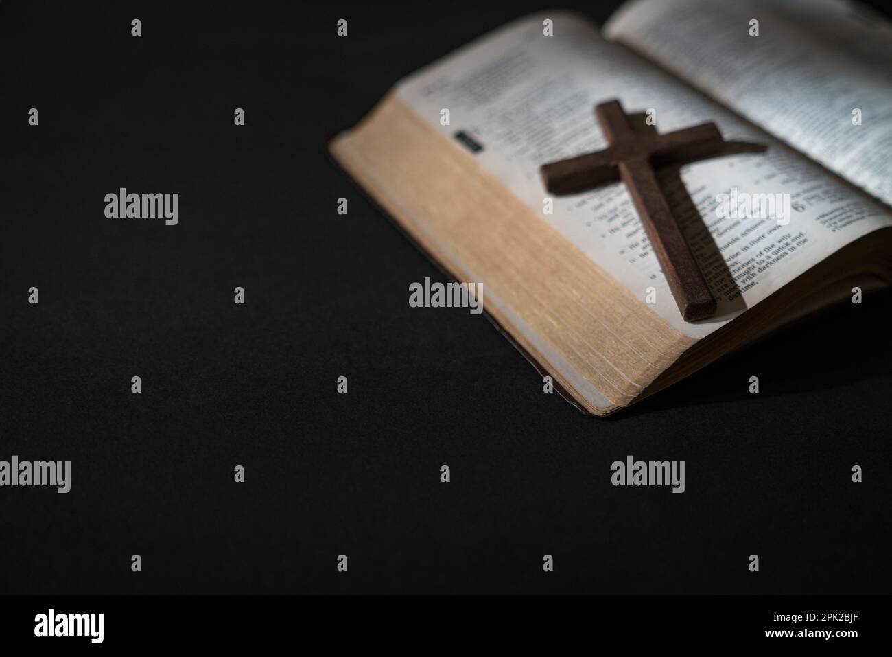 Croce crocifissa in legno sulla cima di una Sacra Bibbia aperta. Messa a fuoco selezionata, copia spazio. Foto Stock