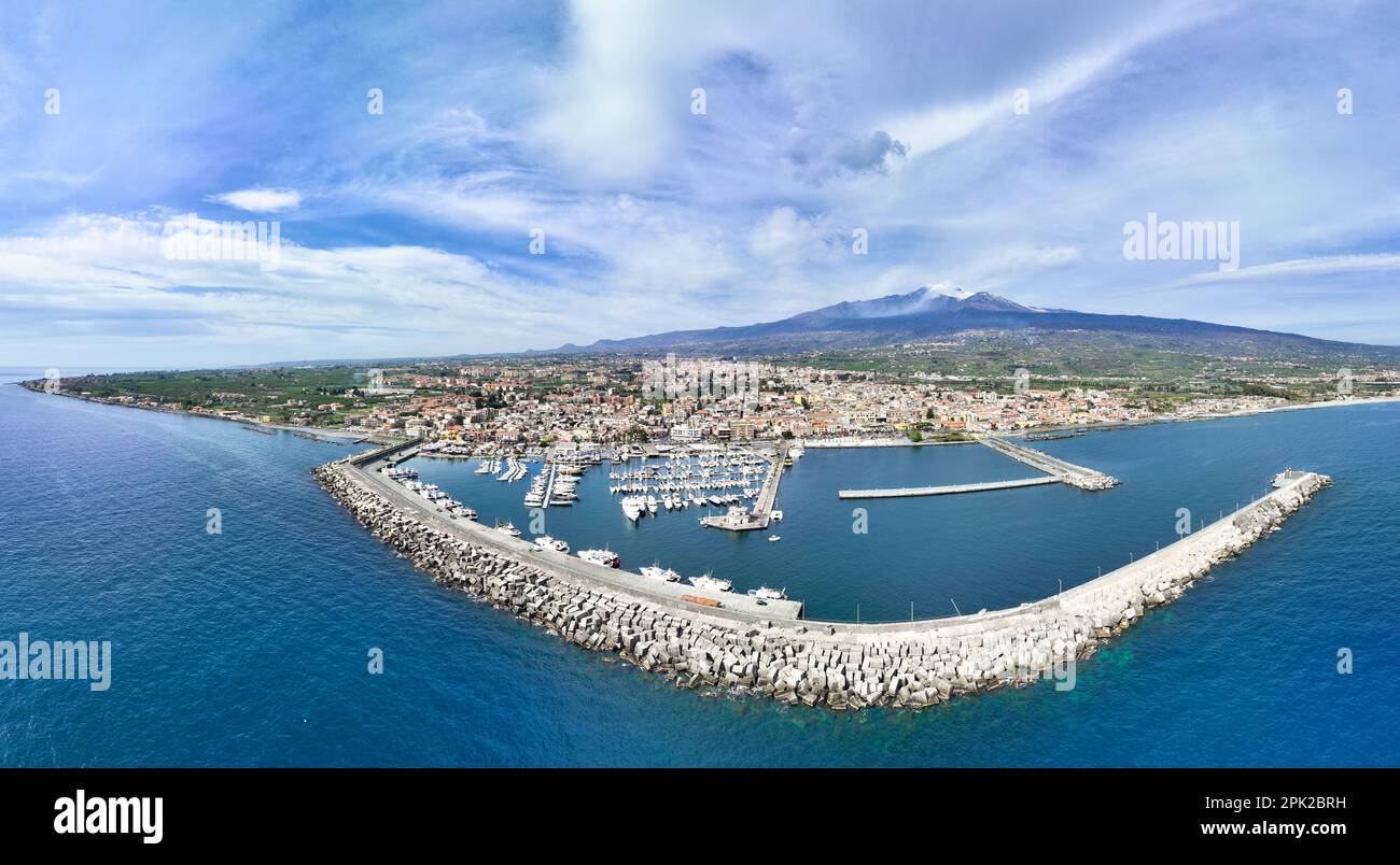 Destinazione estiva Riposto - veduta aerea dall'alto sul porto con barche durante le giornate di sole con vulcano Etna sullo sfondo del mare Foto Stock