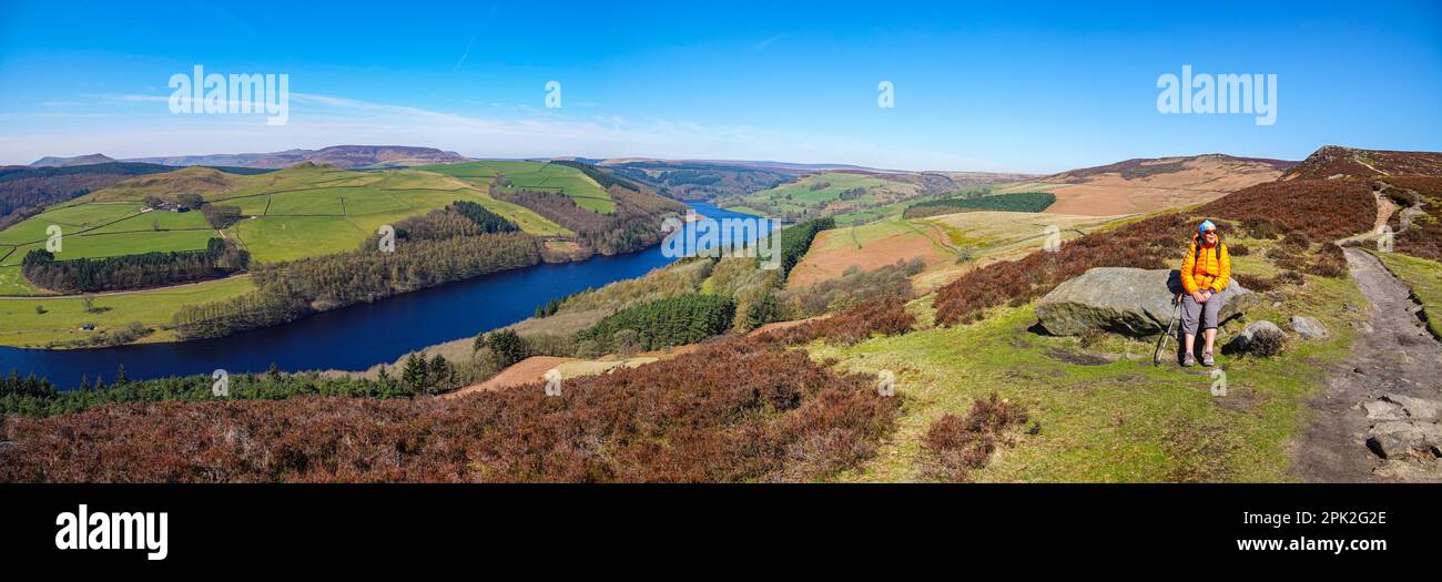 Escursionista femminile camminando lungo Dovestones Edge, sopra il lago artificiale di Ladybower e le dighe di Derwent, Peak District, Derbyshire, Regno Unito Foto Stock