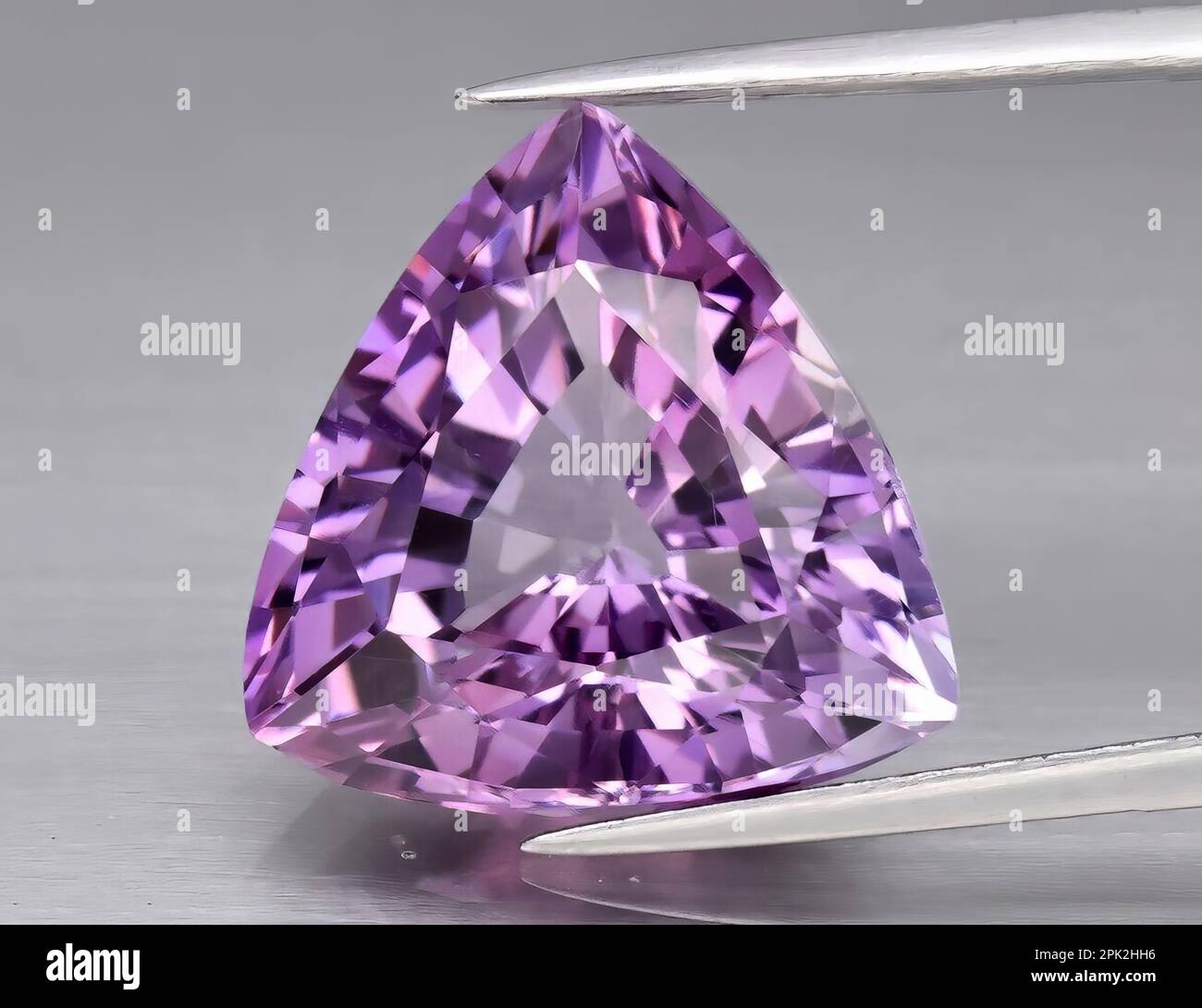 Gemma naturale ametista viola su uno sfondo grigio. Varietà viola di quarzo Foto Stock