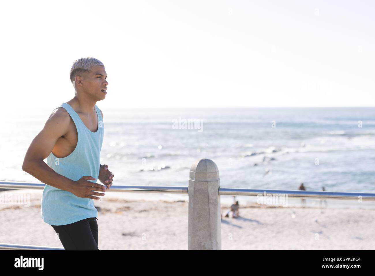 Uomo biraciale che indossa abbigliamento sportivo e corre sul lungomare sul mare Foto Stock