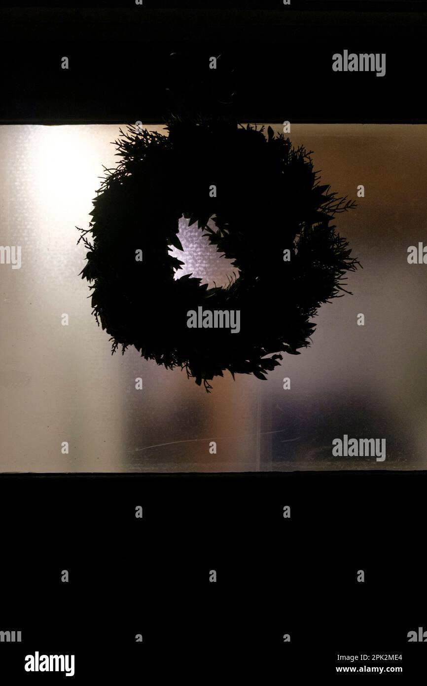 Una porta di casa scura spaventosa con la corona nera di natale. Foto Stock